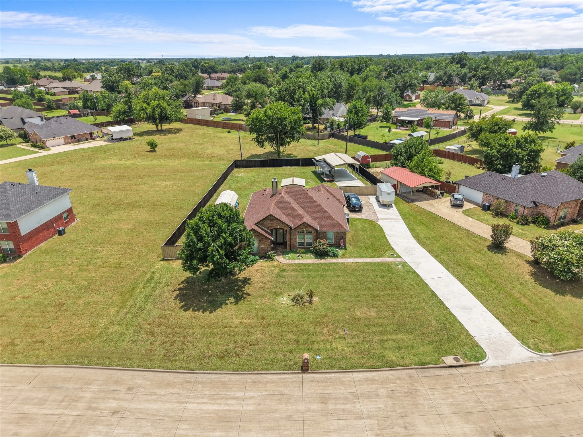 Expansive corner lot featuring a single-story residence with a brown shingle roof and brick exterior