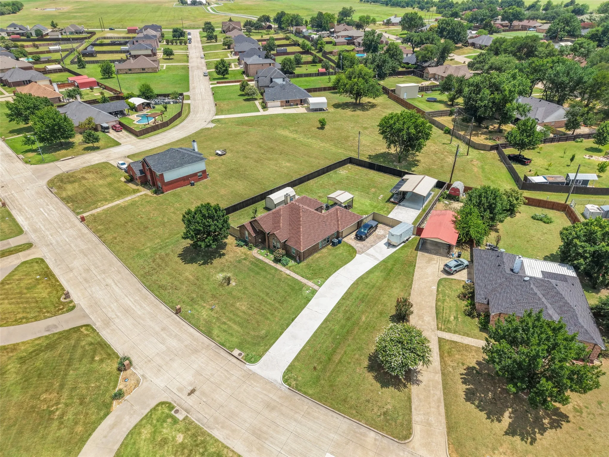 Expansive property featuring a single-story residence with a red tile roof and an extended concrete driveway