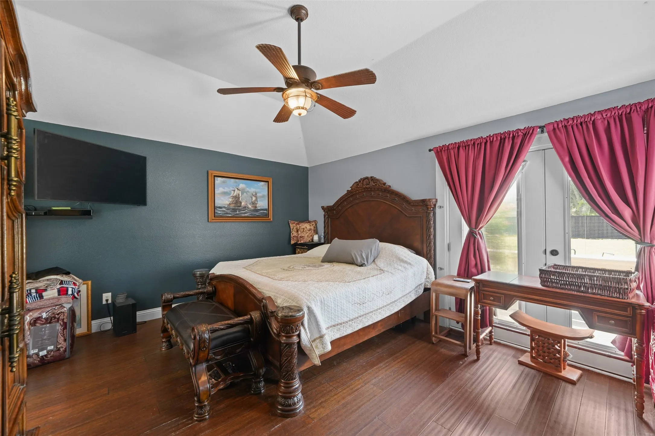 Room featuring wood-finish flooring, a vaulted ceiling, and a ceiling fan with integrated lighting
