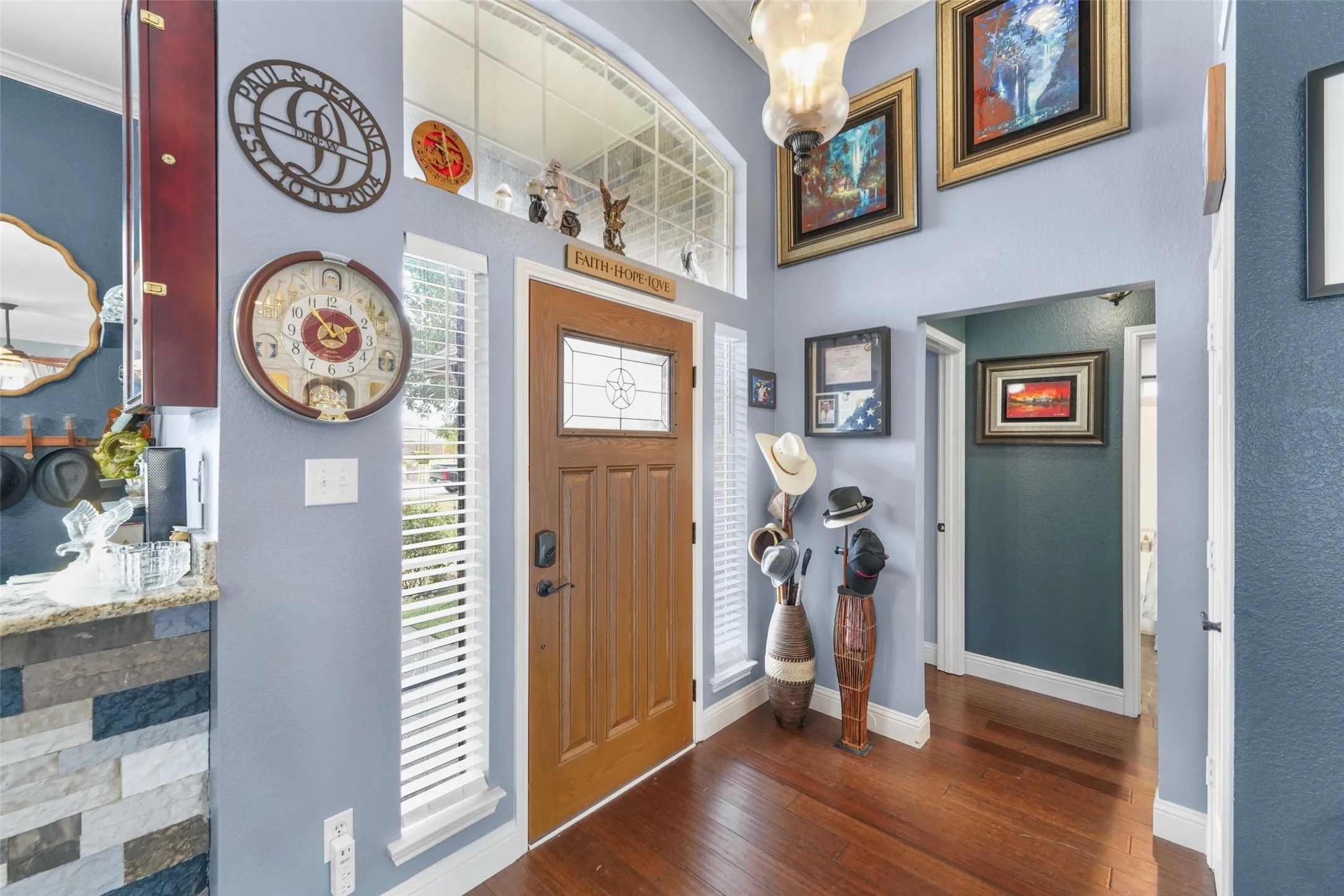 Entryway featuring a wood-finish door with decorative glass inserts, an arched transom window, and vertical window panels with blinds
