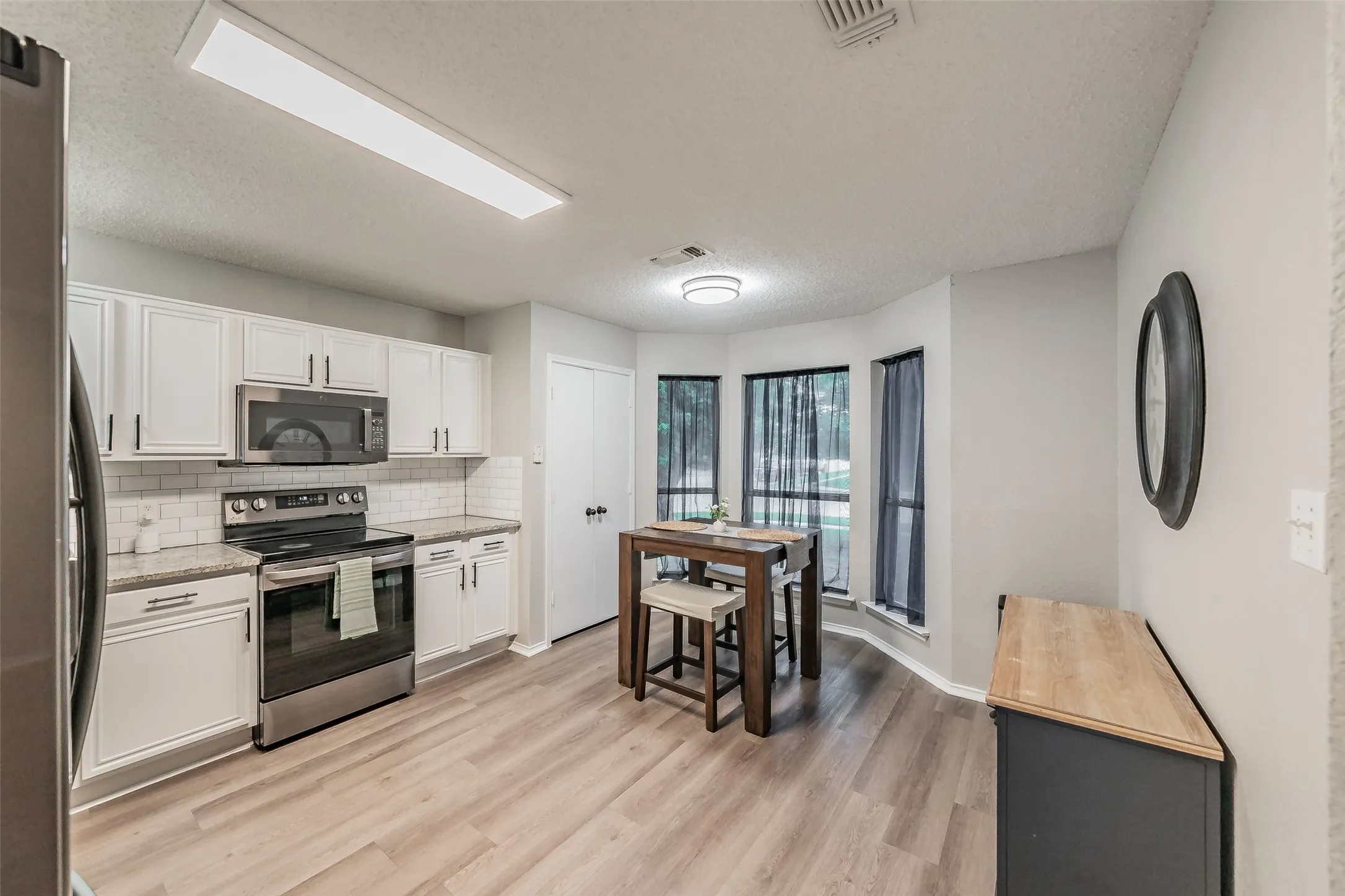 Updated kitchen featuring white cabinetry, stainless steel appliances, a subway tile backsplash