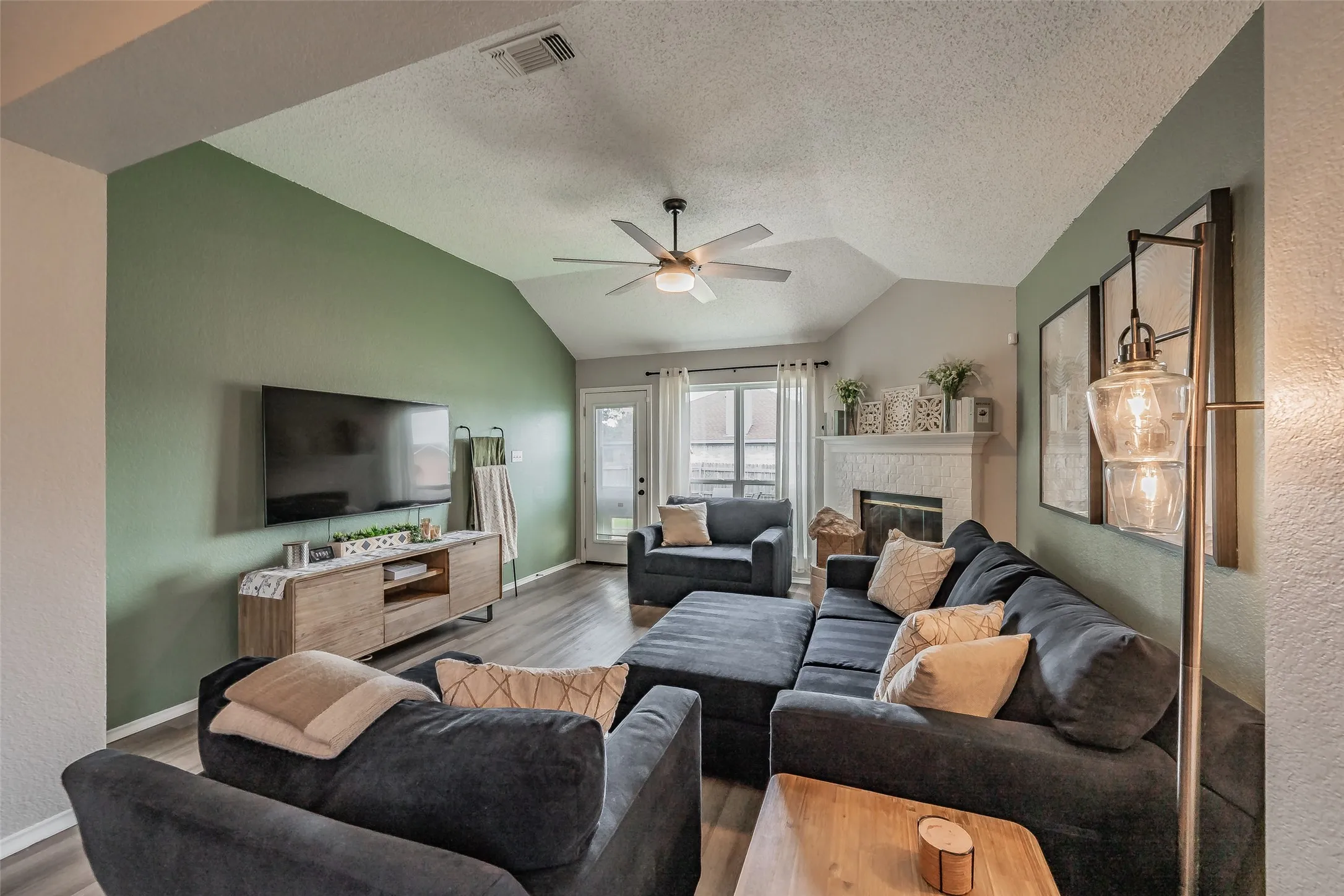 Living area featuring a ceiling fan, a brick fireplace with a brick hearth and wood mantel.