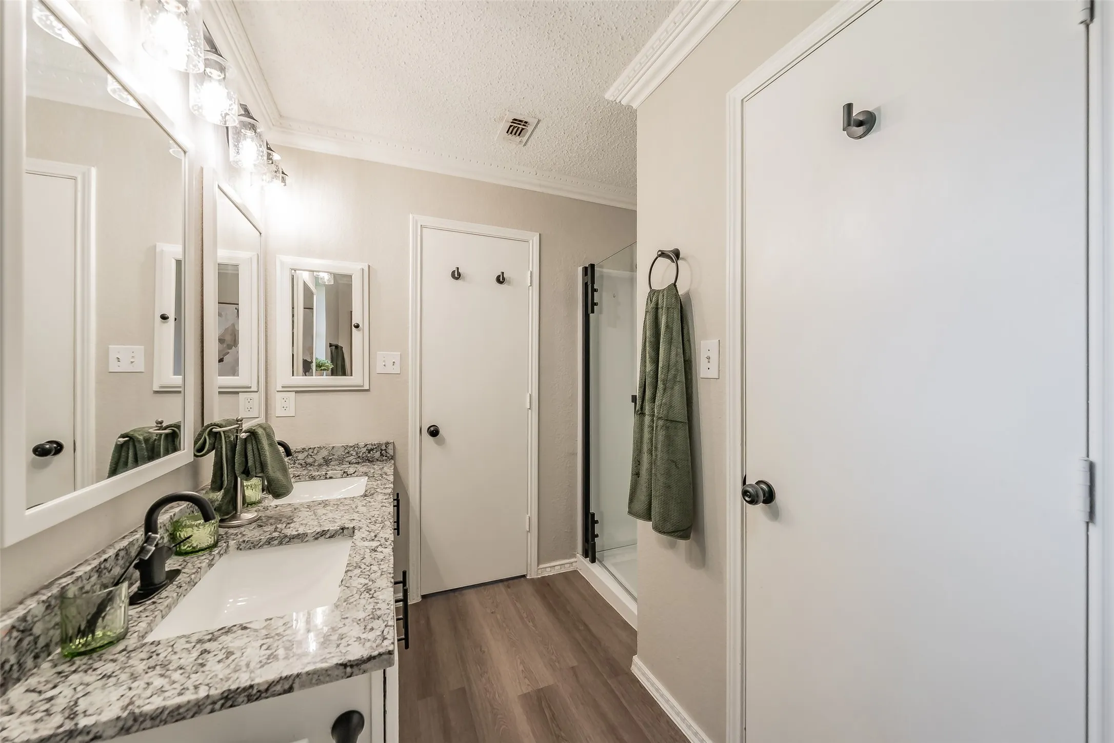 Bathroom featuring a dual vanity with granite-patterned countertops and undermount sinks, flanked by rectangular mirrors and illuminated by a multi-bulb vanity light fixture