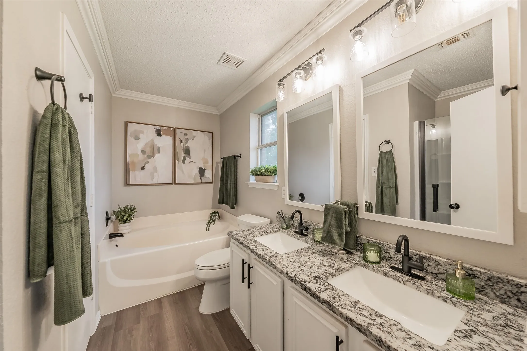 Primary bath with double vanity with granite-style countertops and matte black fixtures