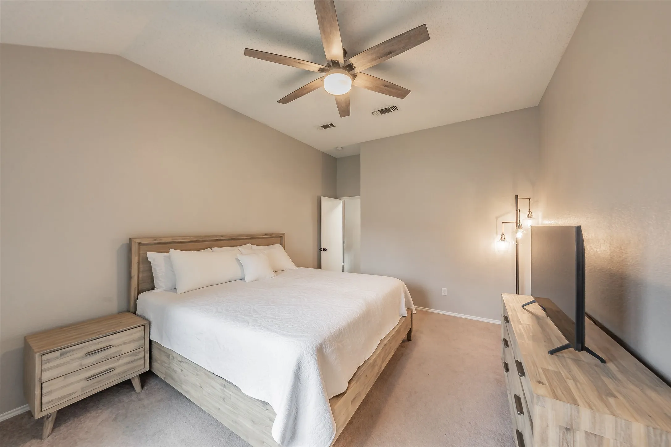 Primary bedroom a ceiling fan, neutral wall paint, and carpet flooring
