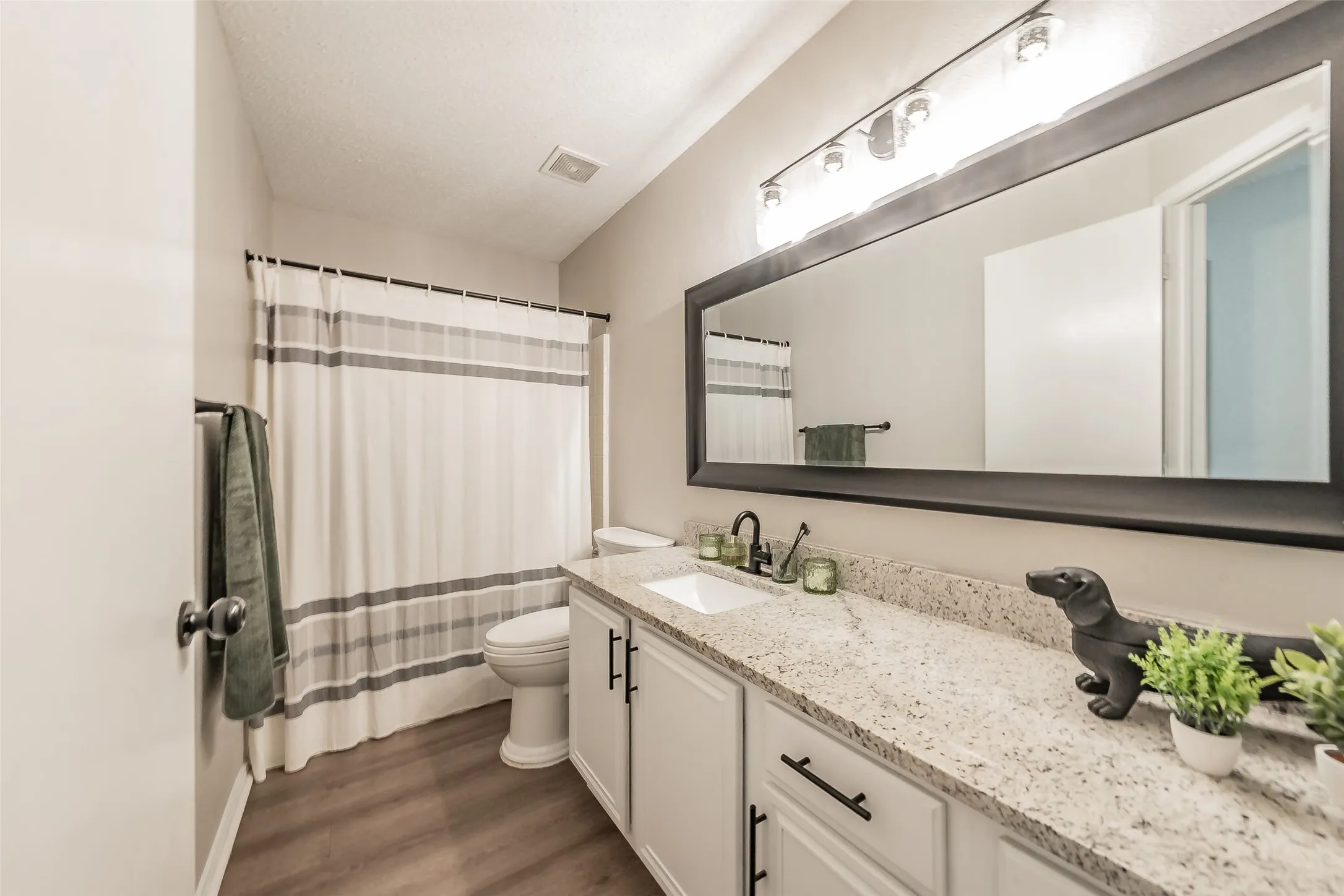 Spacious bathroom featuring an extended vanity with a light-toned speckled countertop, undermount sink, and dark-finish fixtures