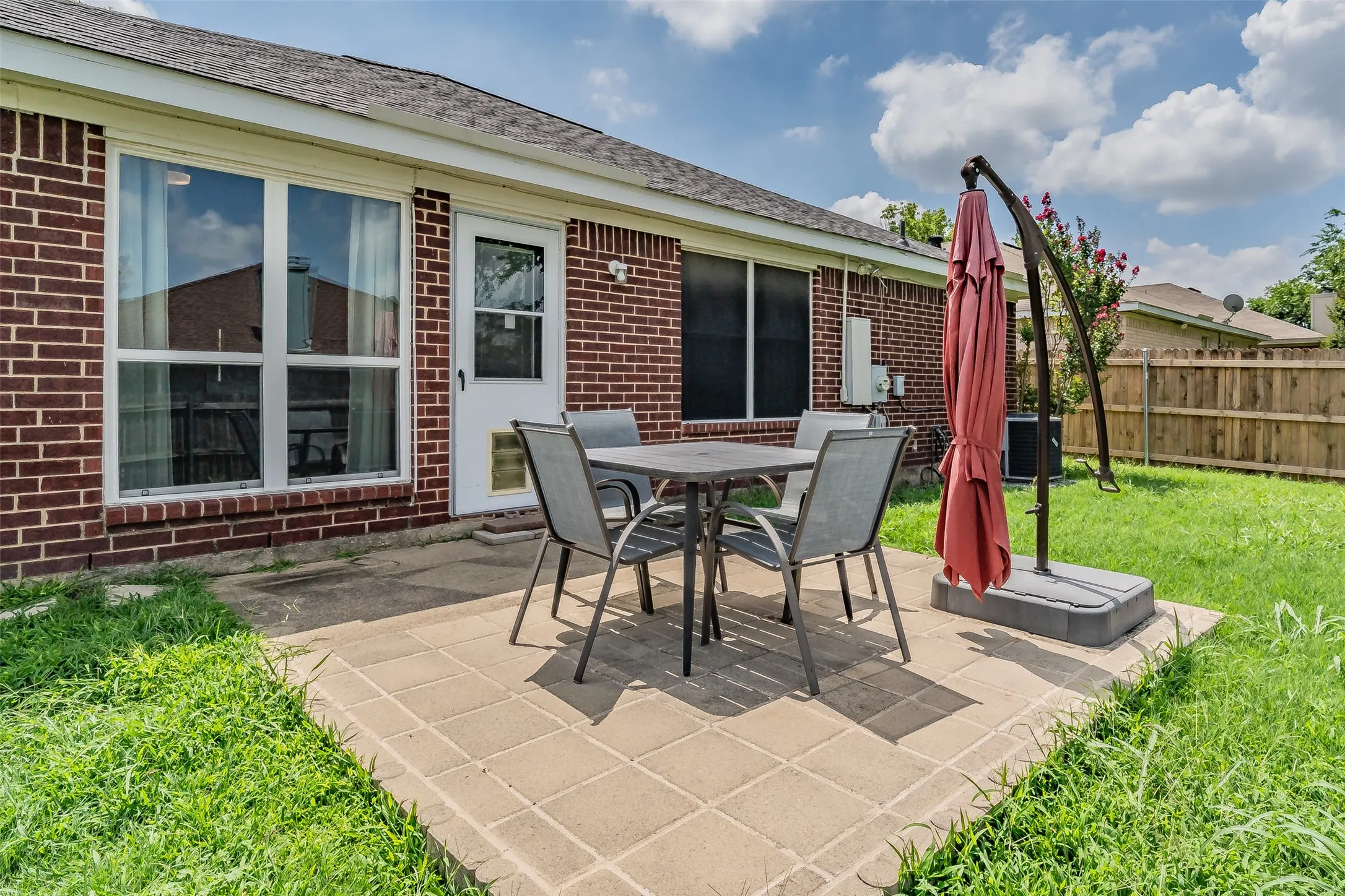 Brick exterior featuring a rear patio with paver flooring and a manicured lawn