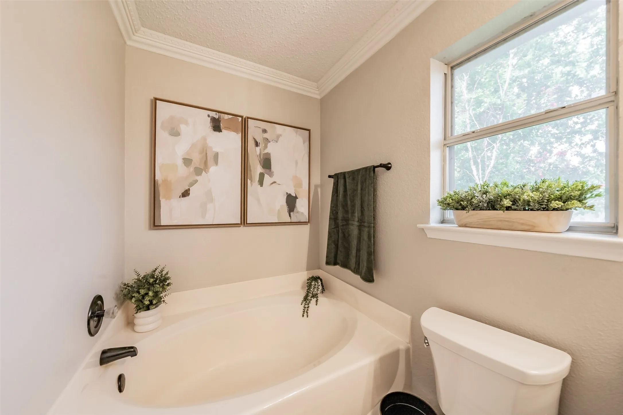 Primary bath with soaking tub with matte black fixtures and crown molding