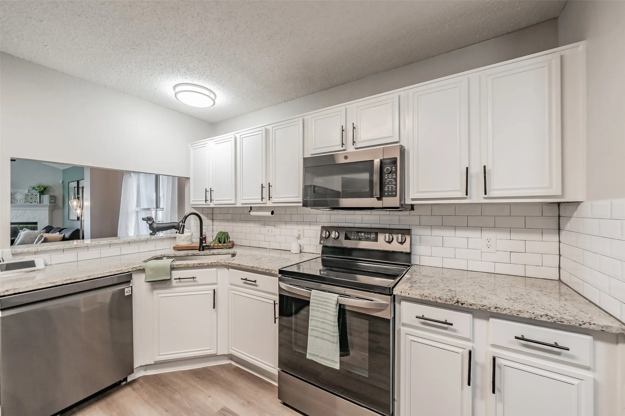 Kitchen featuring white cabinetry, light-toned countertops, stainless steel appliances, a subway tile backsplash