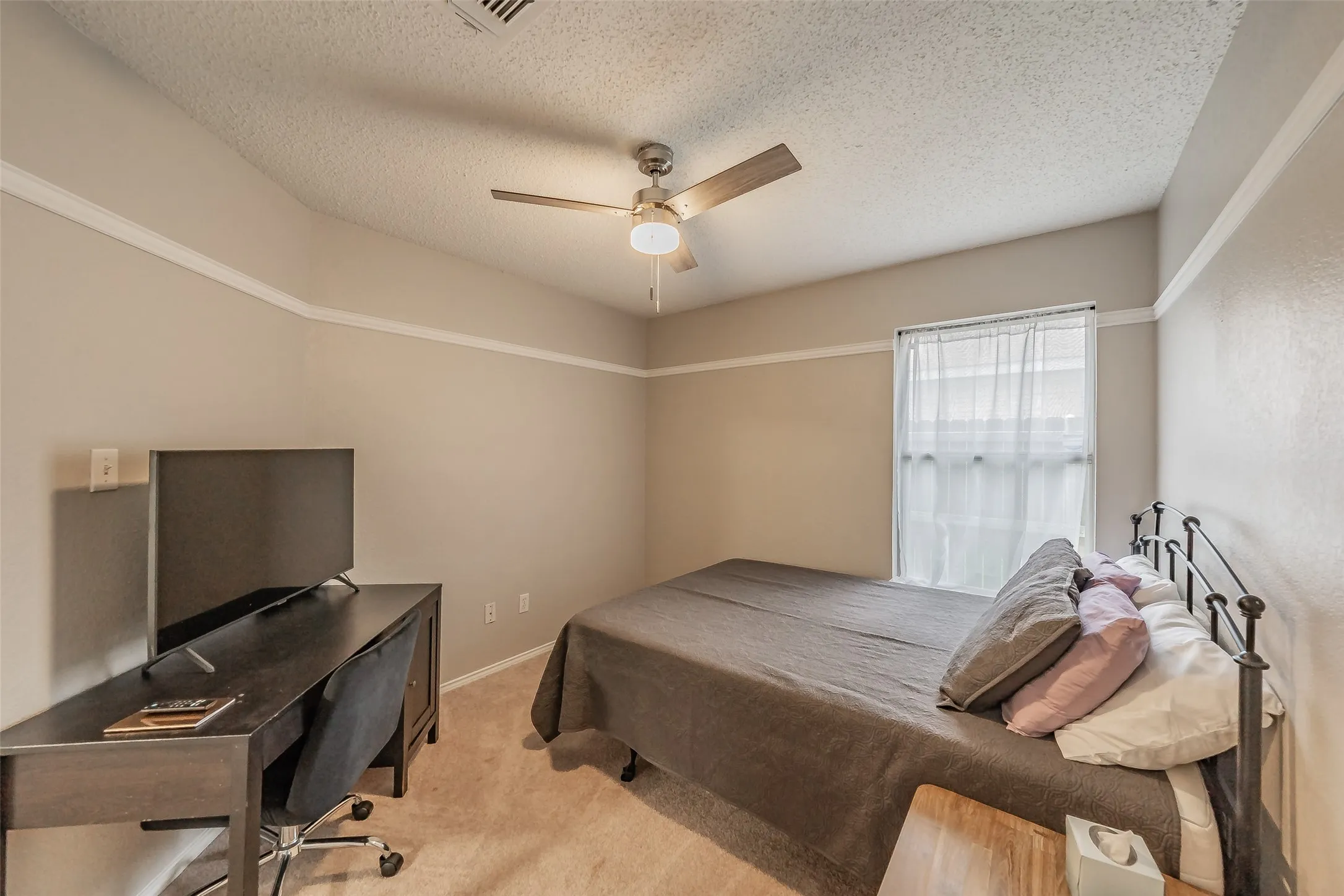 Carpeted room with a ceiling fan light fixture