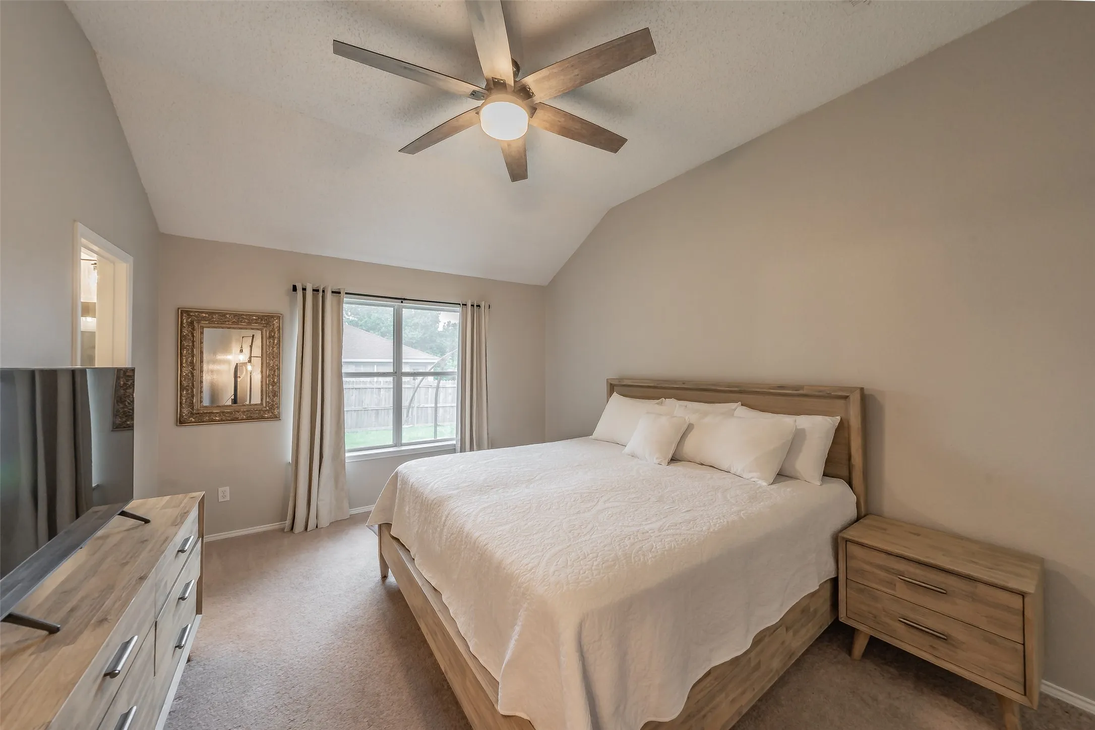 Carpeted room featuring a vaulted ceiling and a ceiling fan