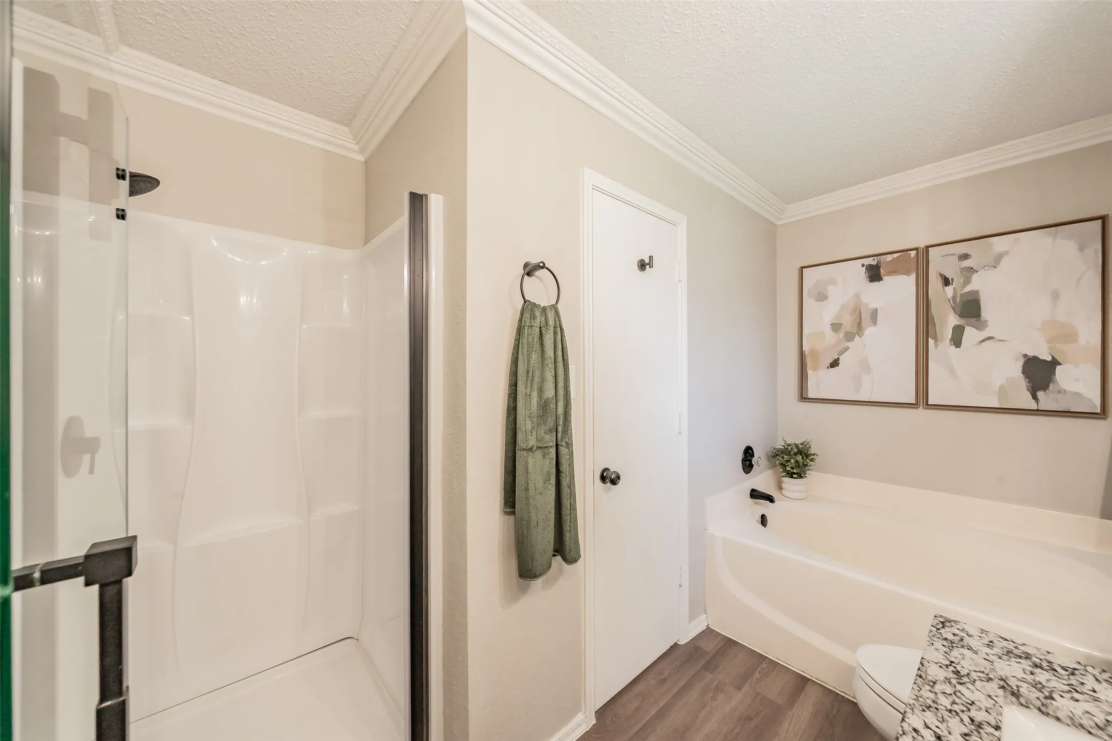 Full bathroom featuring a walk-in shower with dark bronze hardware, a built-in bathtub with dark bronze fixtures, a white vanity with a granite countertop, and crown molding