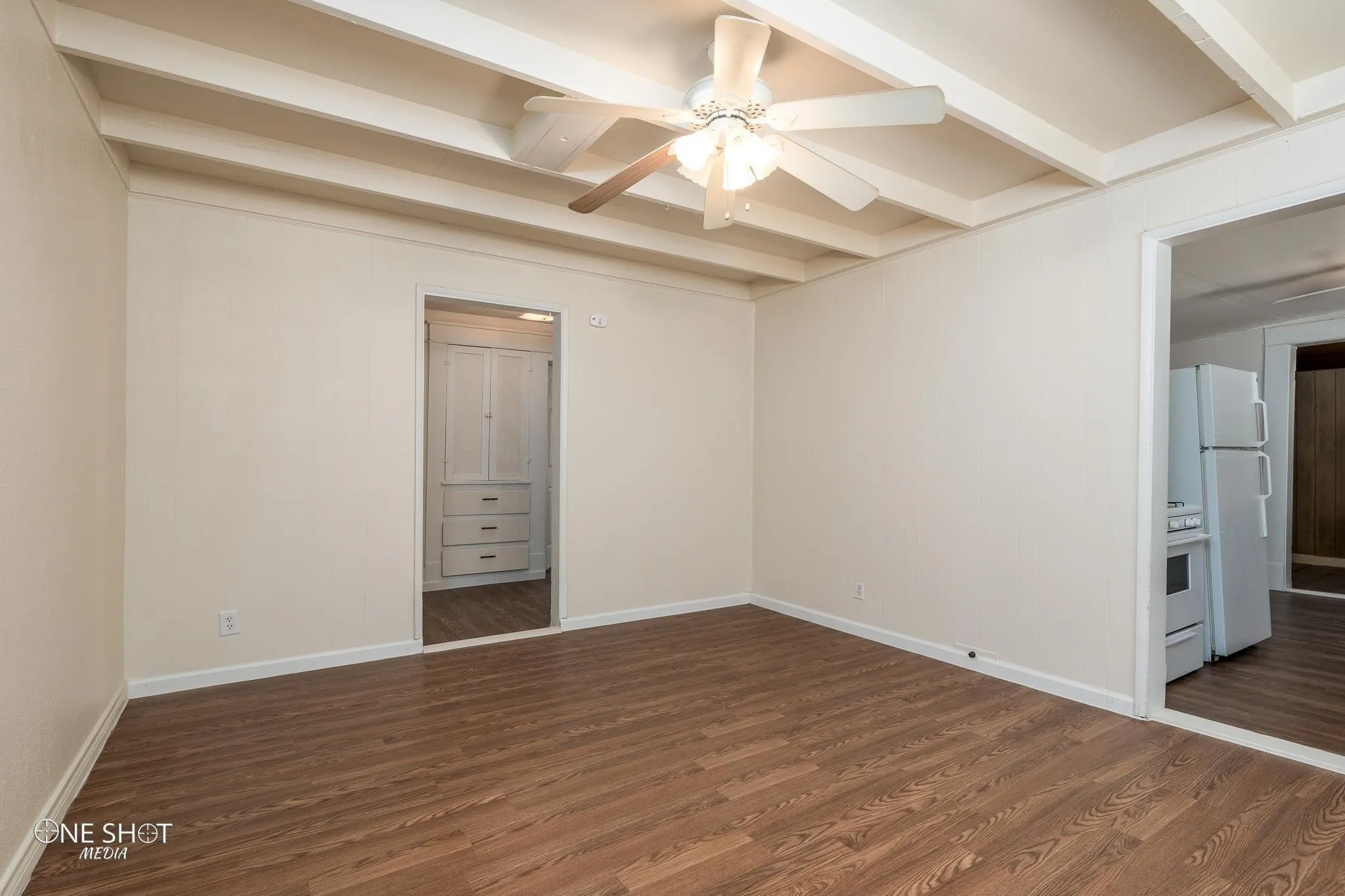 Unfurnished room featuring beamed ceiling, dark hardwood / wood-style floors, and ceiling fan