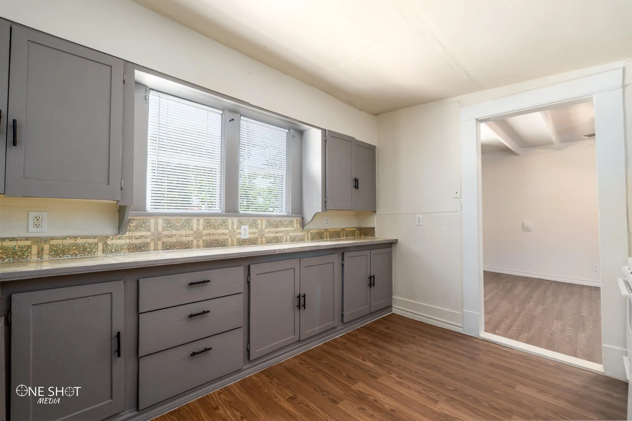 Kitchen featuring beam ceiling, tasteful backsplash, wood-type flooring, and gray cabinetry
