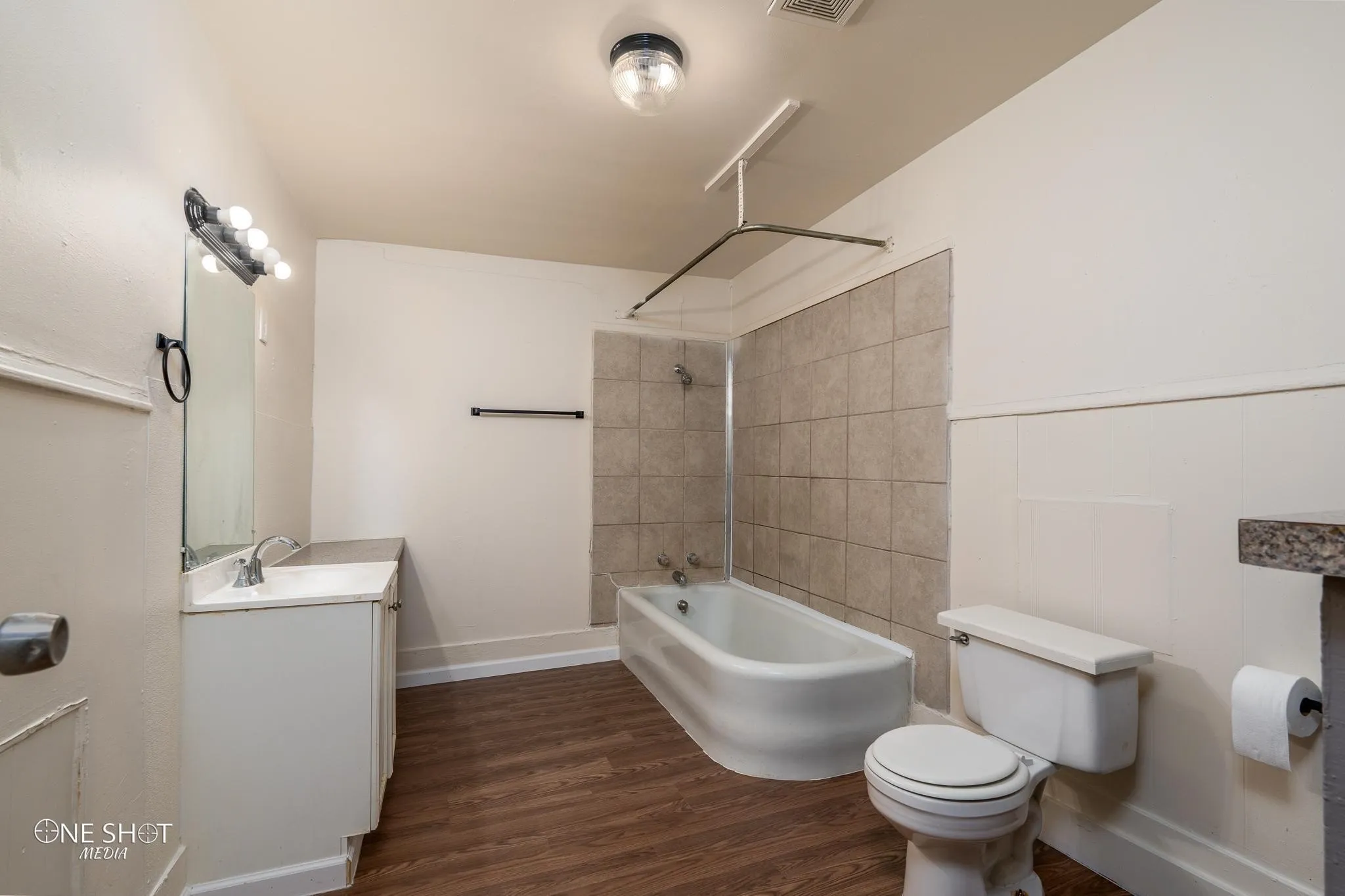 Full bathroom with hardwood / wood-style floors, vanity, toilet, and tiled shower / bath