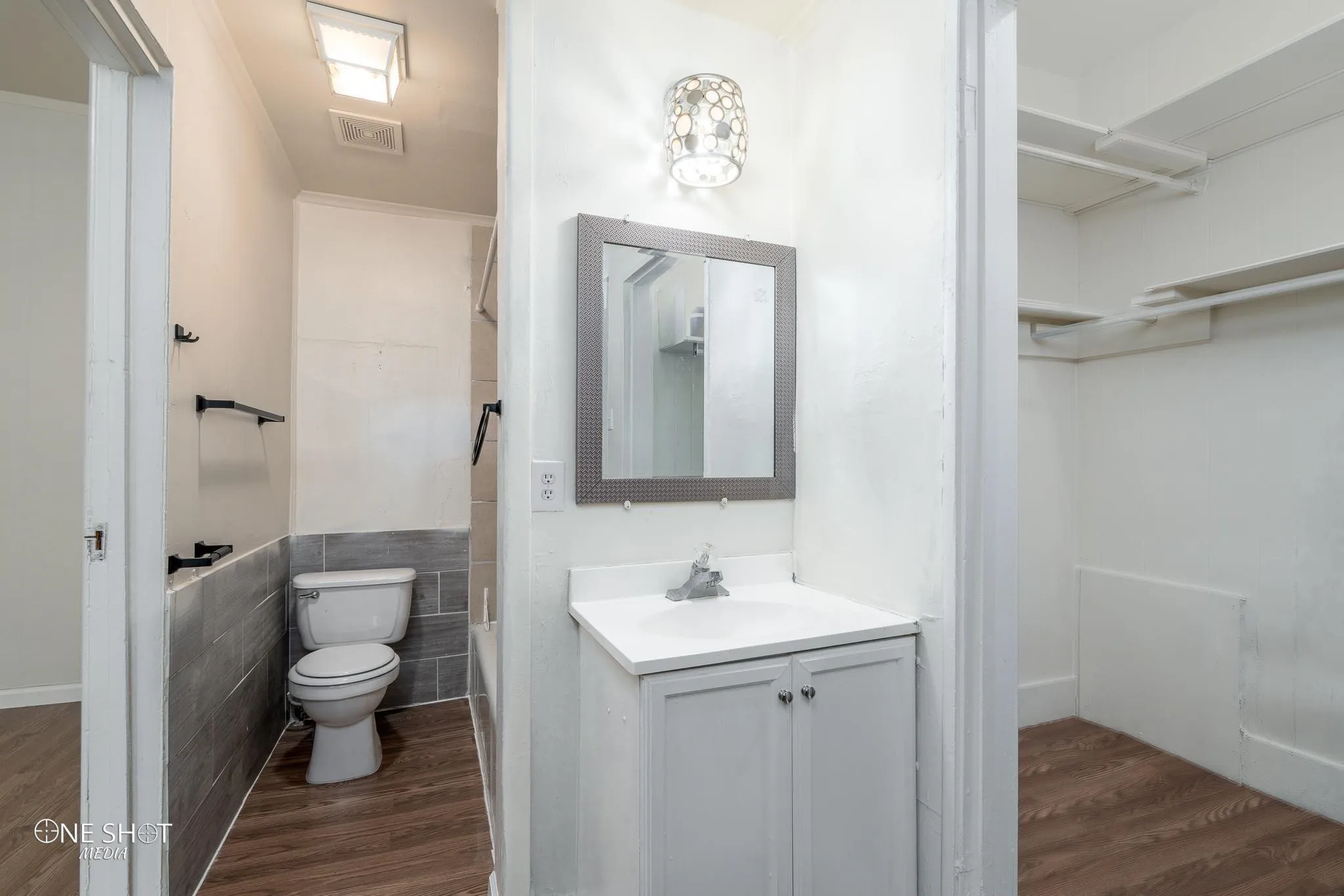 Full bathroom with hardwood / wood-style floors, vanity, toilet, and tile walls