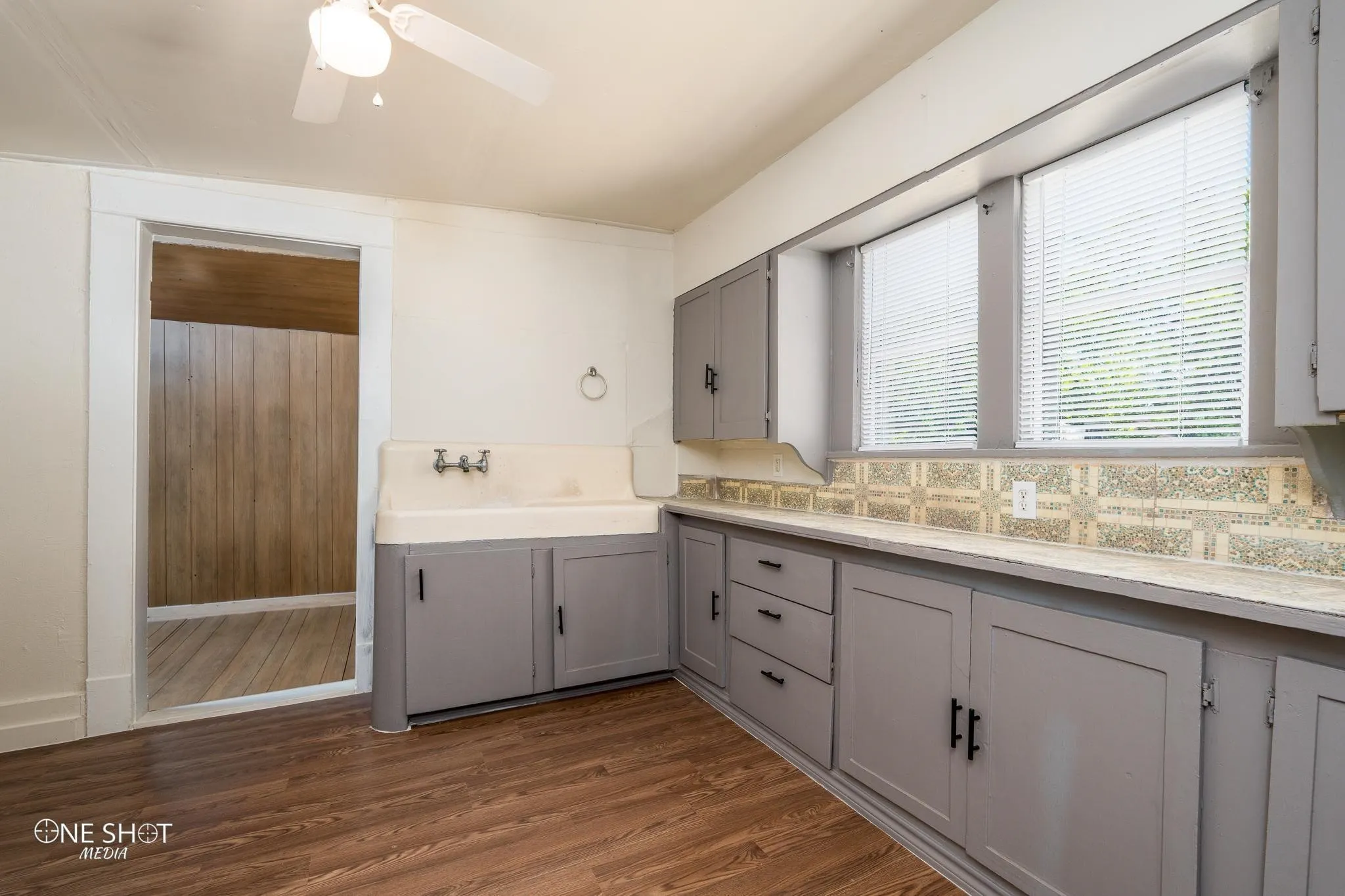 Kitchen with gray cabinetry, hardwood / wood-style flooring, and backsplash