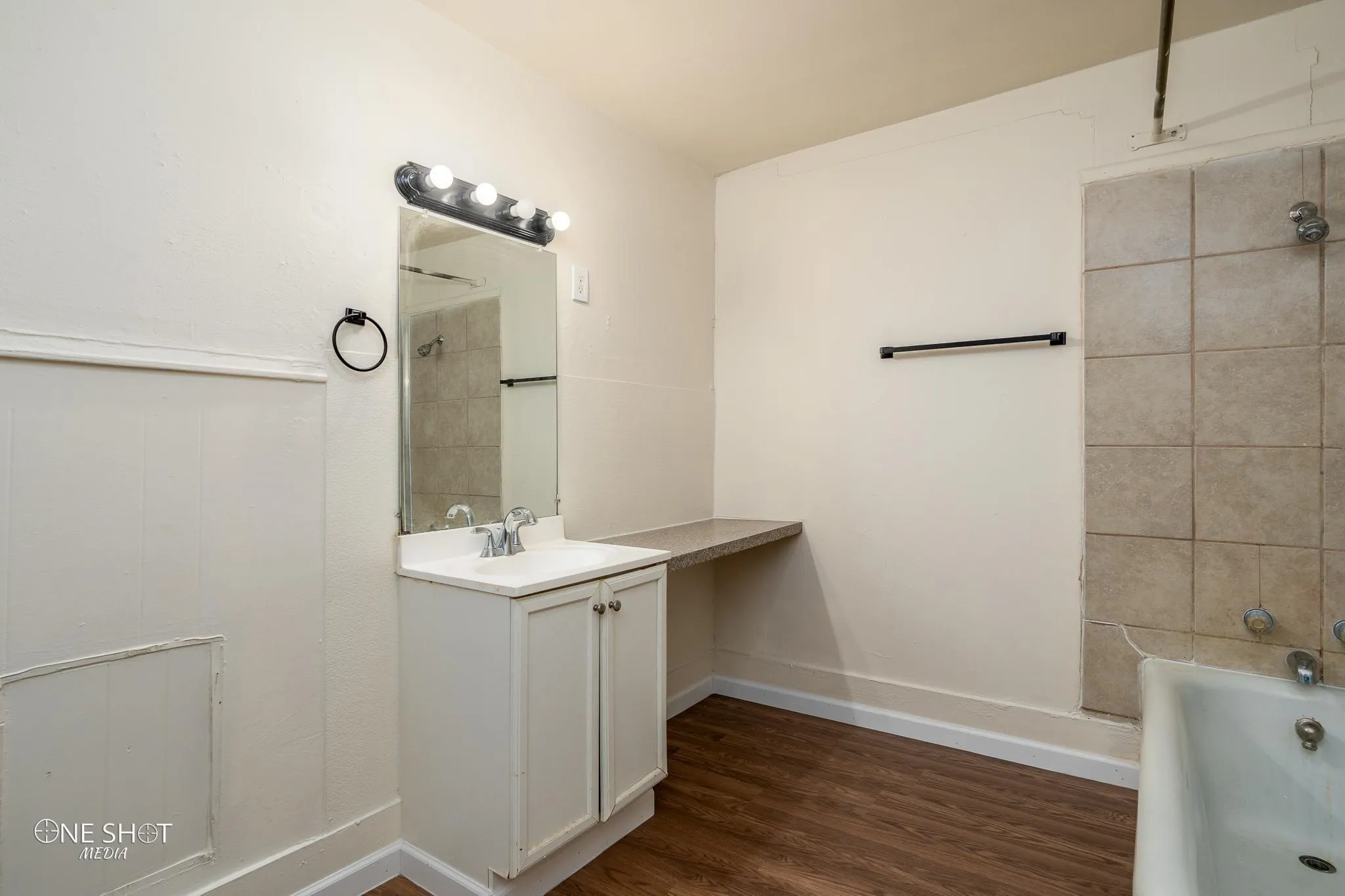 Bathroom with hardwood / wood-style floors, tiled shower / bath combo, and large vanity