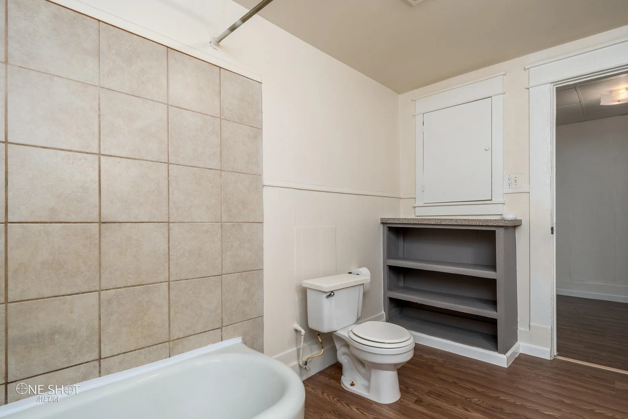 Bathroom with tile walls, hardwood / wood-style flooring, toilet, and shower / bathtub combination