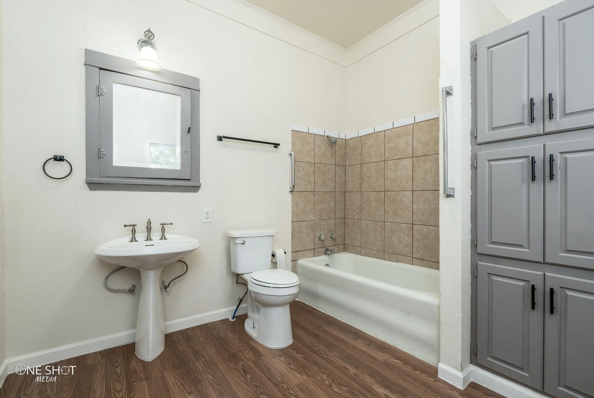 Bathroom with hardwood / wood-style flooring, toilet, tiled shower / bath combo, and ornamental molding