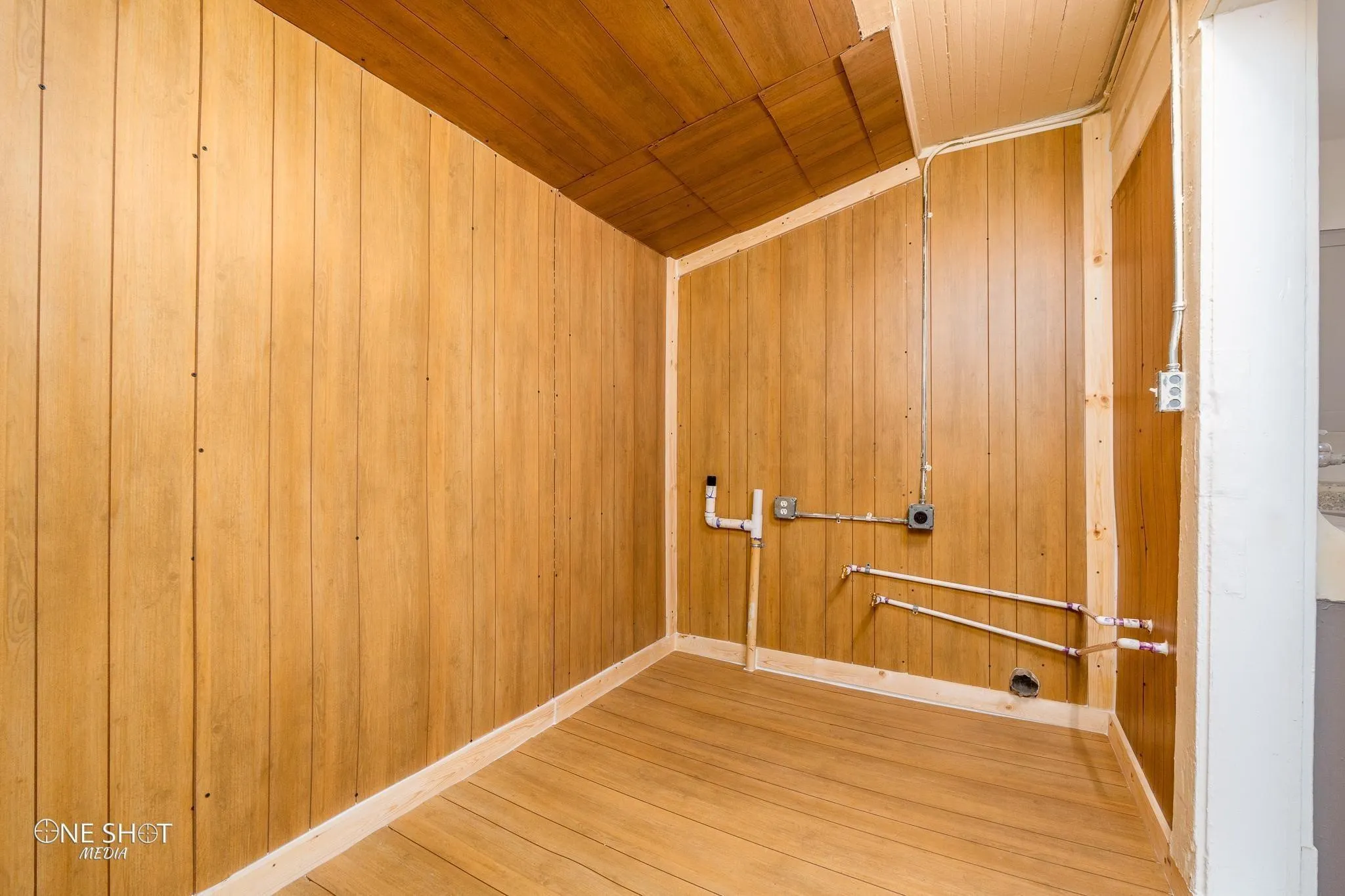 Laundry room with wooden ceiling, wooden walls, and hardwood / wood-style flooring