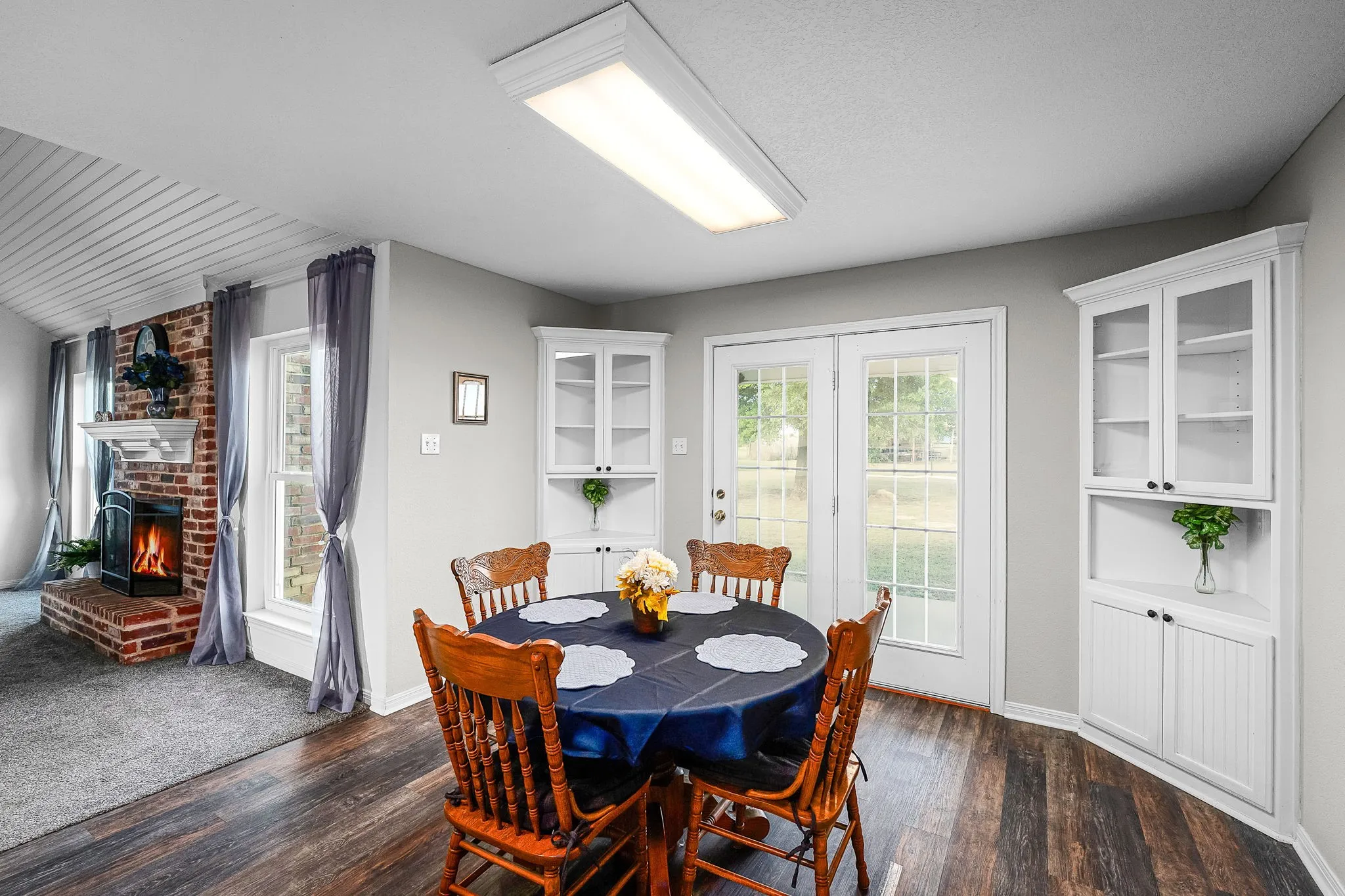 Dining area featuring wood-finish flooring, white built-in cabinetry with glass-front uppers, and French doors leading to​​‌​​​​‌​​‌‌​‌‌​​​‌‌​‌​‌​‌​​​‌​​ exterior