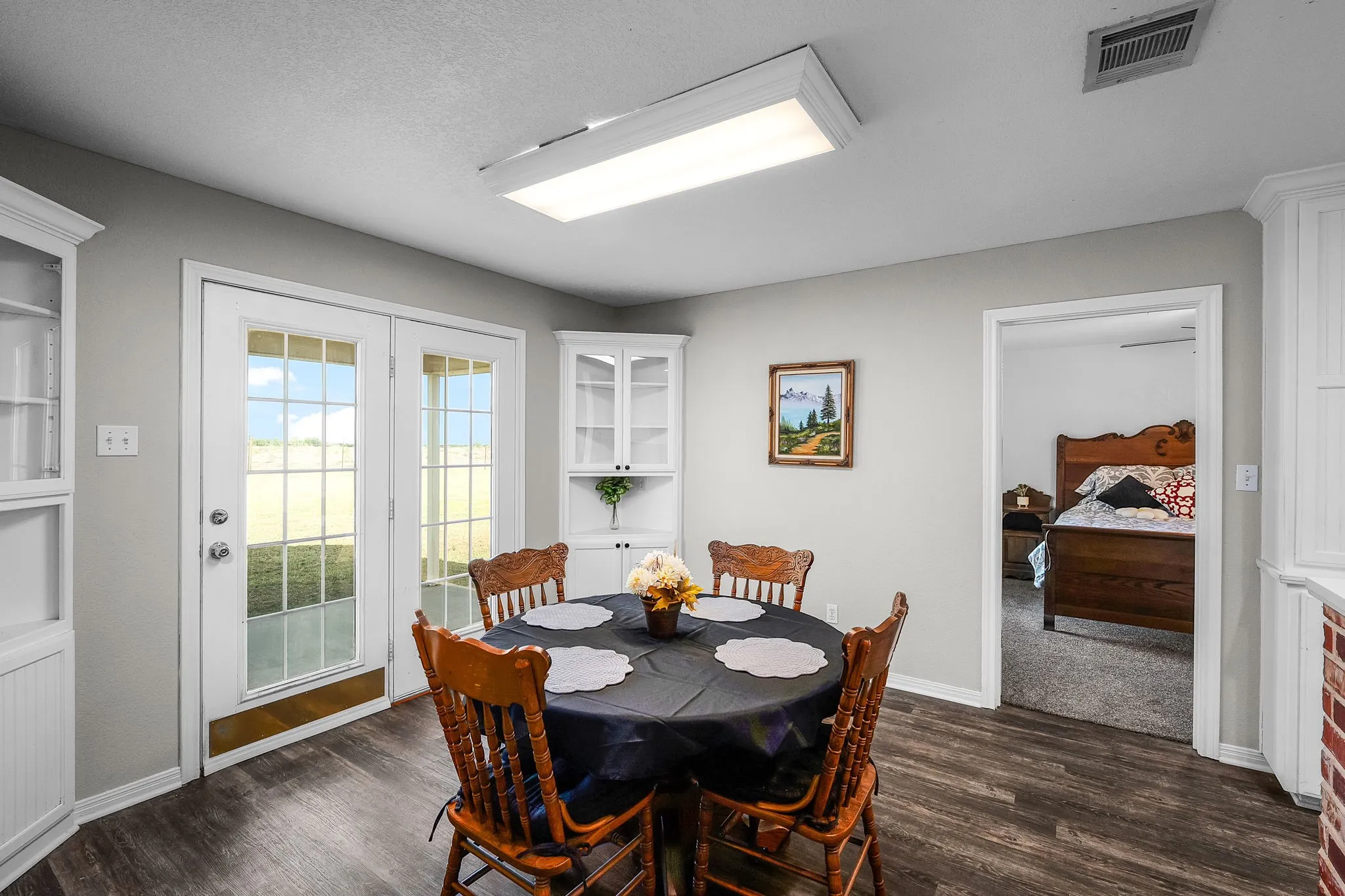 French doors opening to the exterior, wood-finish flooring, white built-in cabinetry, and neutral wall paint