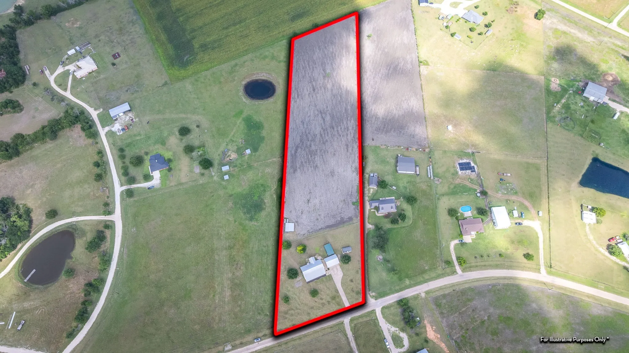 Expansive aerial view of a property featuring a primary residence, multiple outbuildings, an elongated field, and a private pond