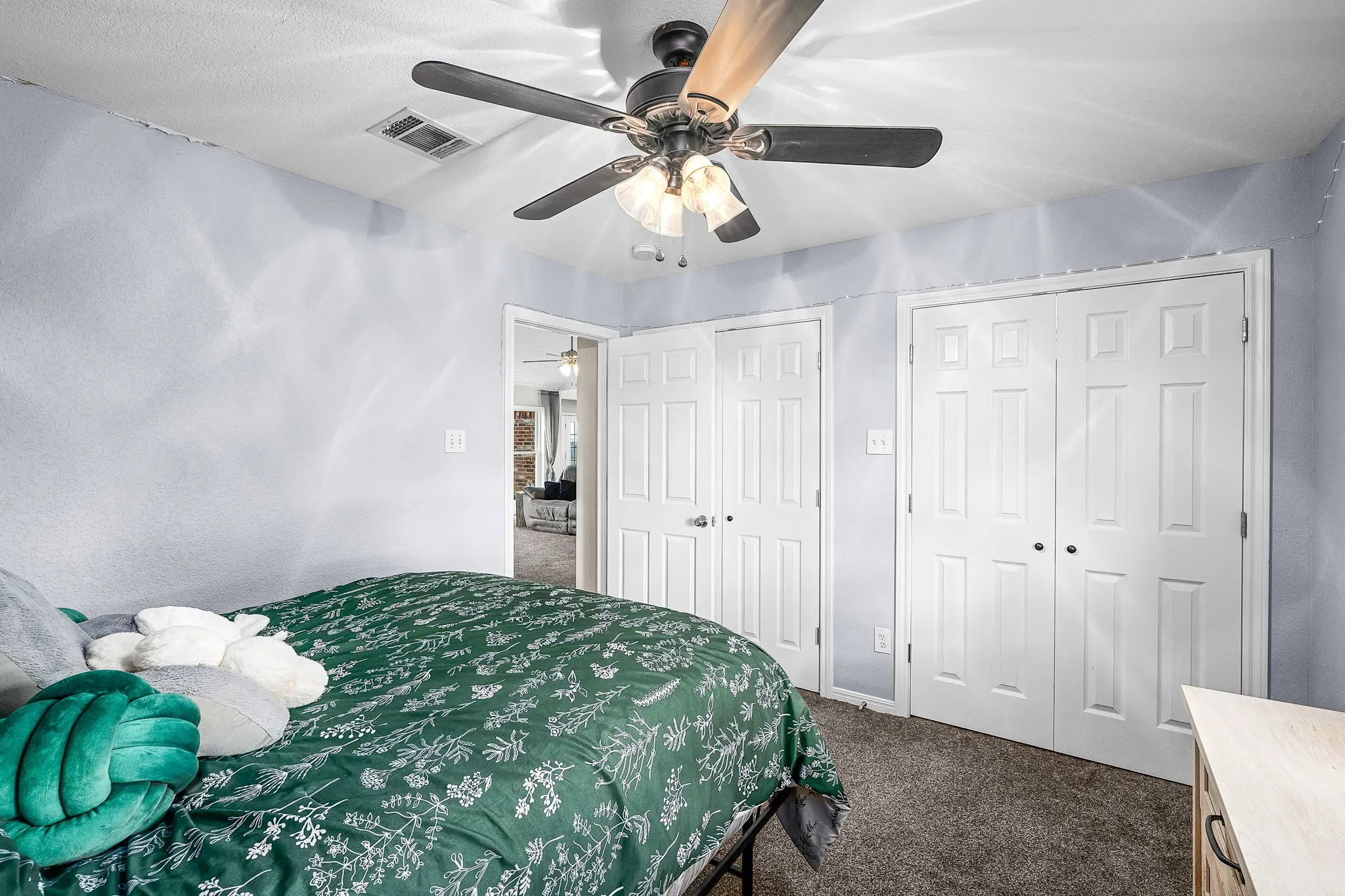 Bedroom featuring a ceiling fan with integrated lighting, textured walls, and carpet flooring