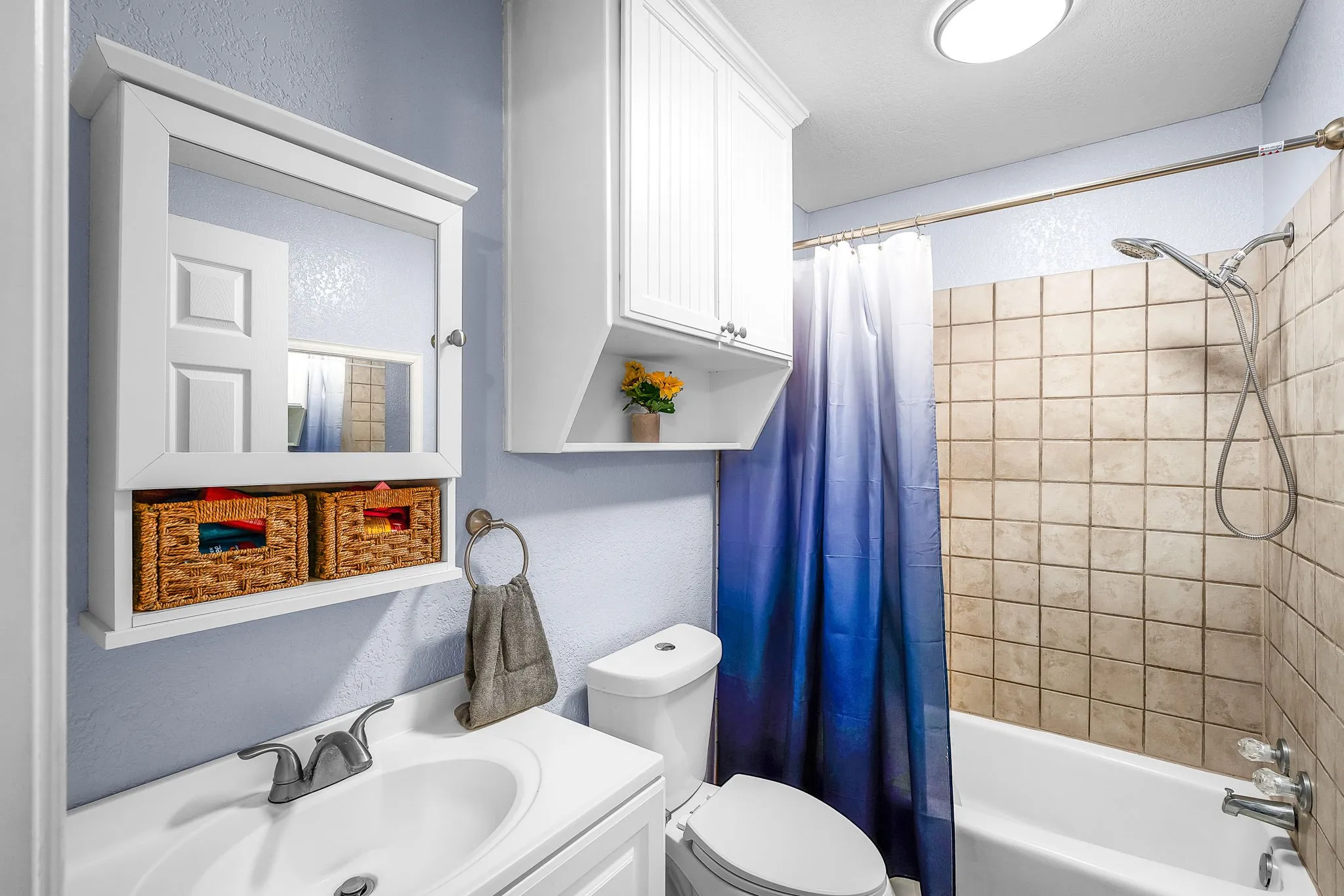 Bathroom featuring a vanity with an integrated sink, polished chrome faucet, and white cabinetry