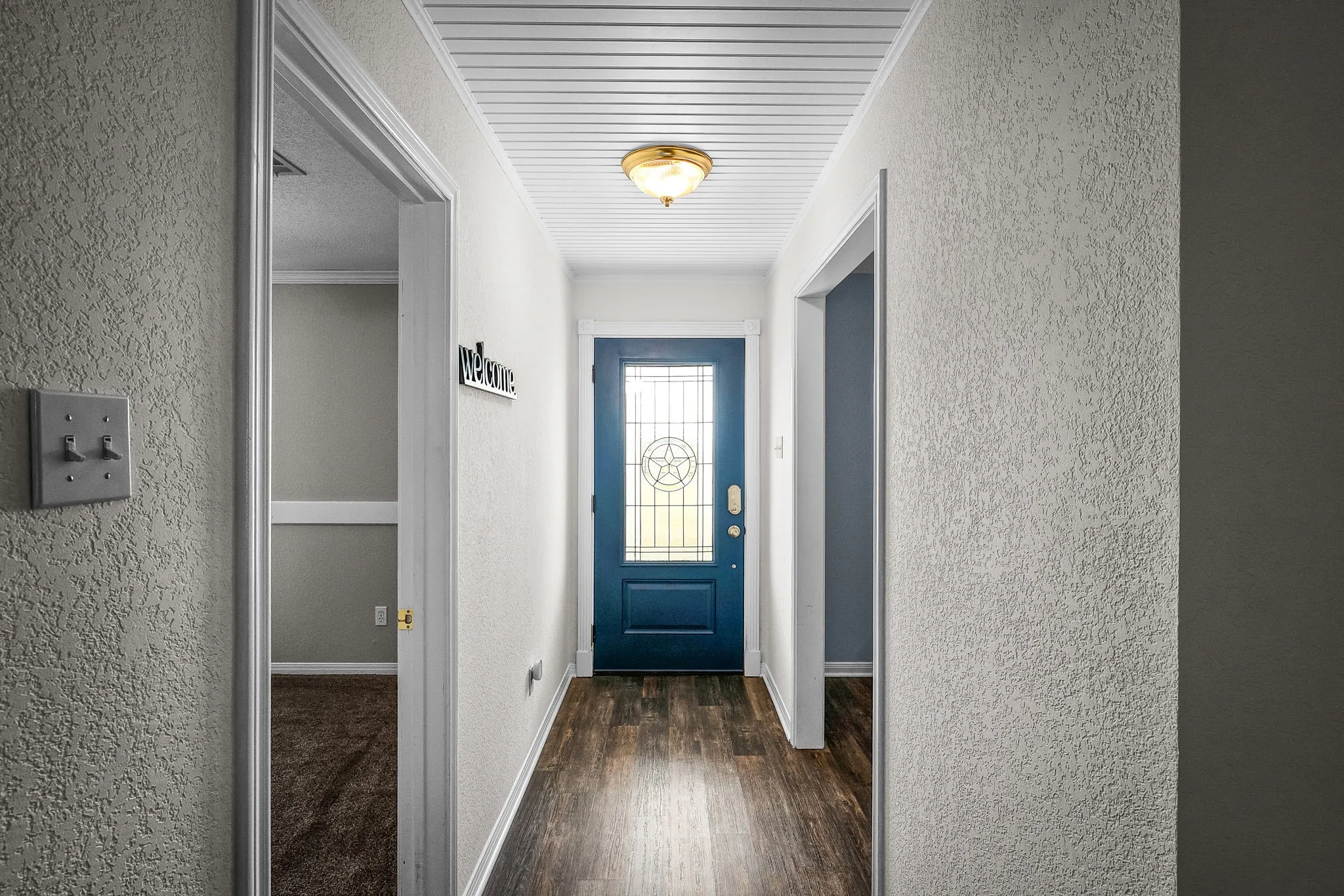 Entryway featuring a dark blue door with decorative glass, wood-finish flooring, and a white beadboard ceiling