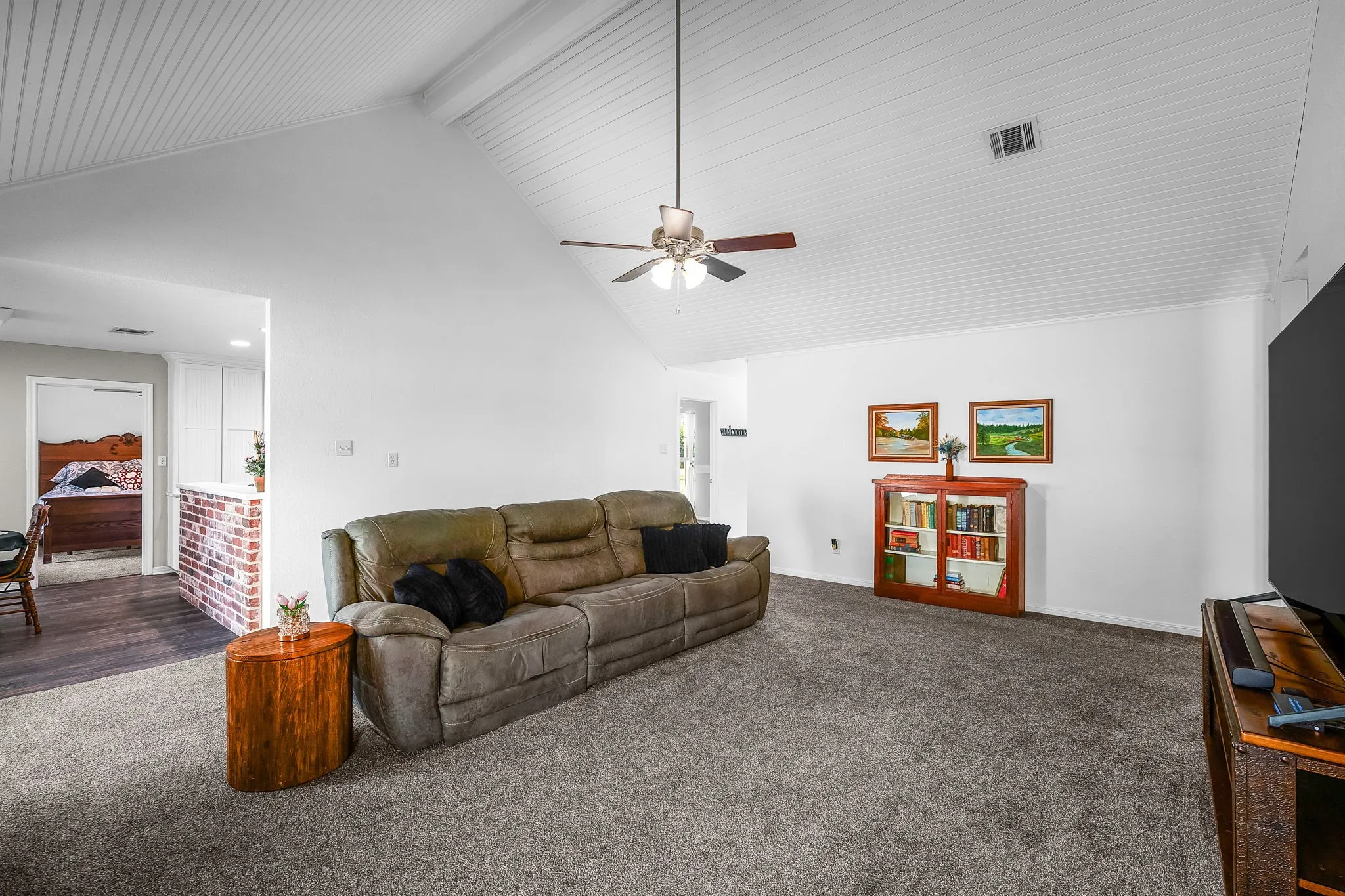Vaulted ceiling with white plank finish and a ceiling fan
