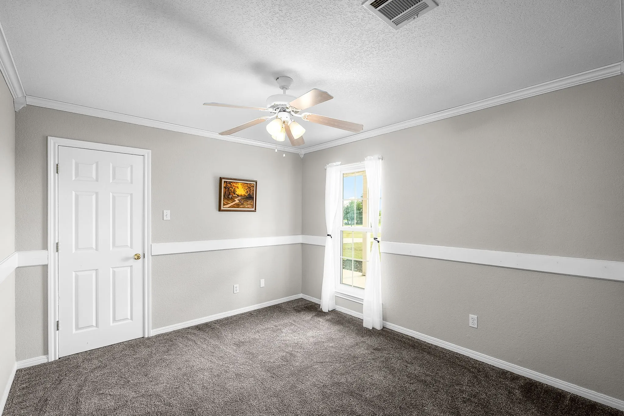 Carpeted room with a single window, white trim, and a ceiling fan