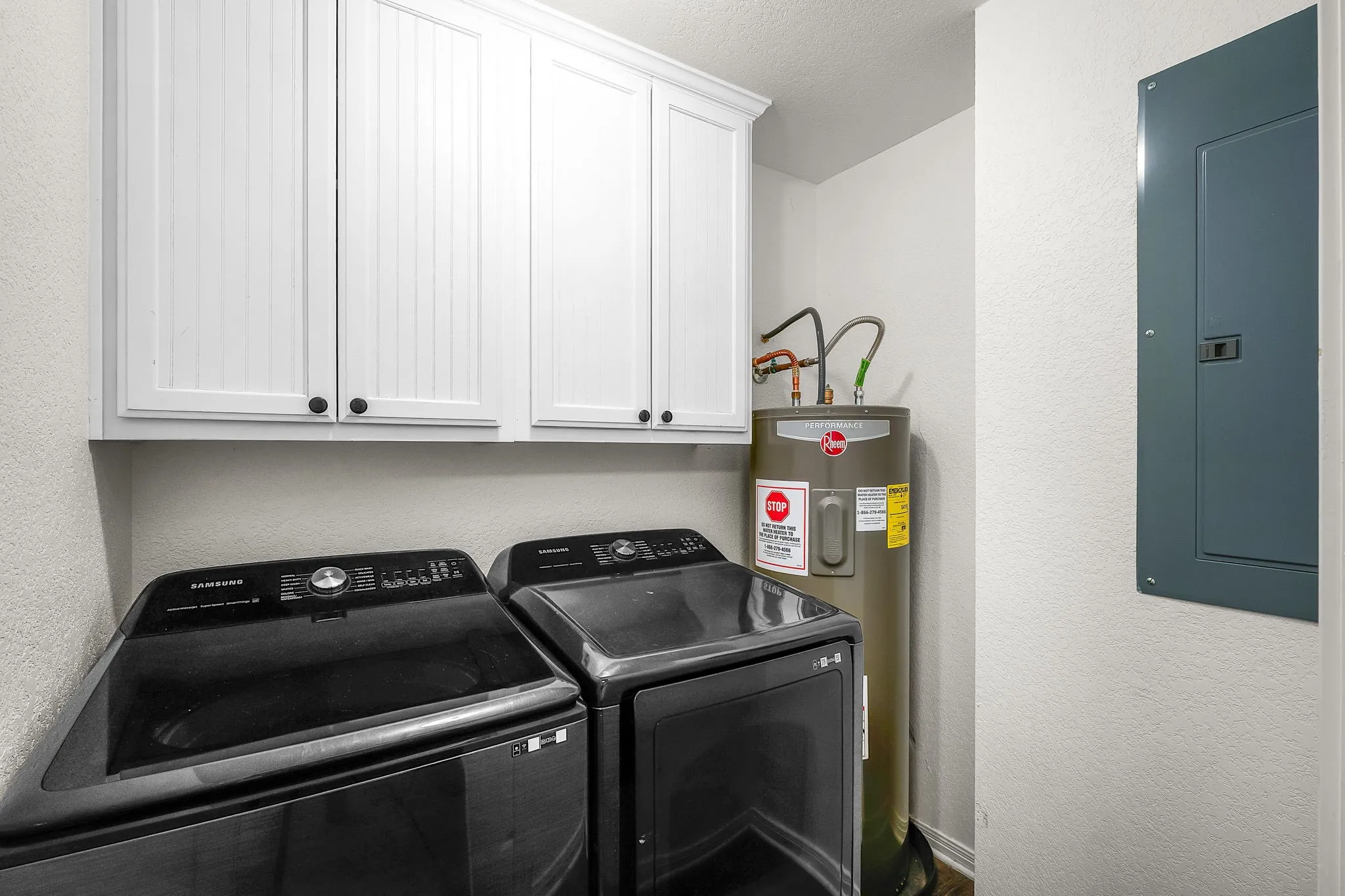 Utility area featuring white shaker-style cabinetry with dark hardware and a water heater