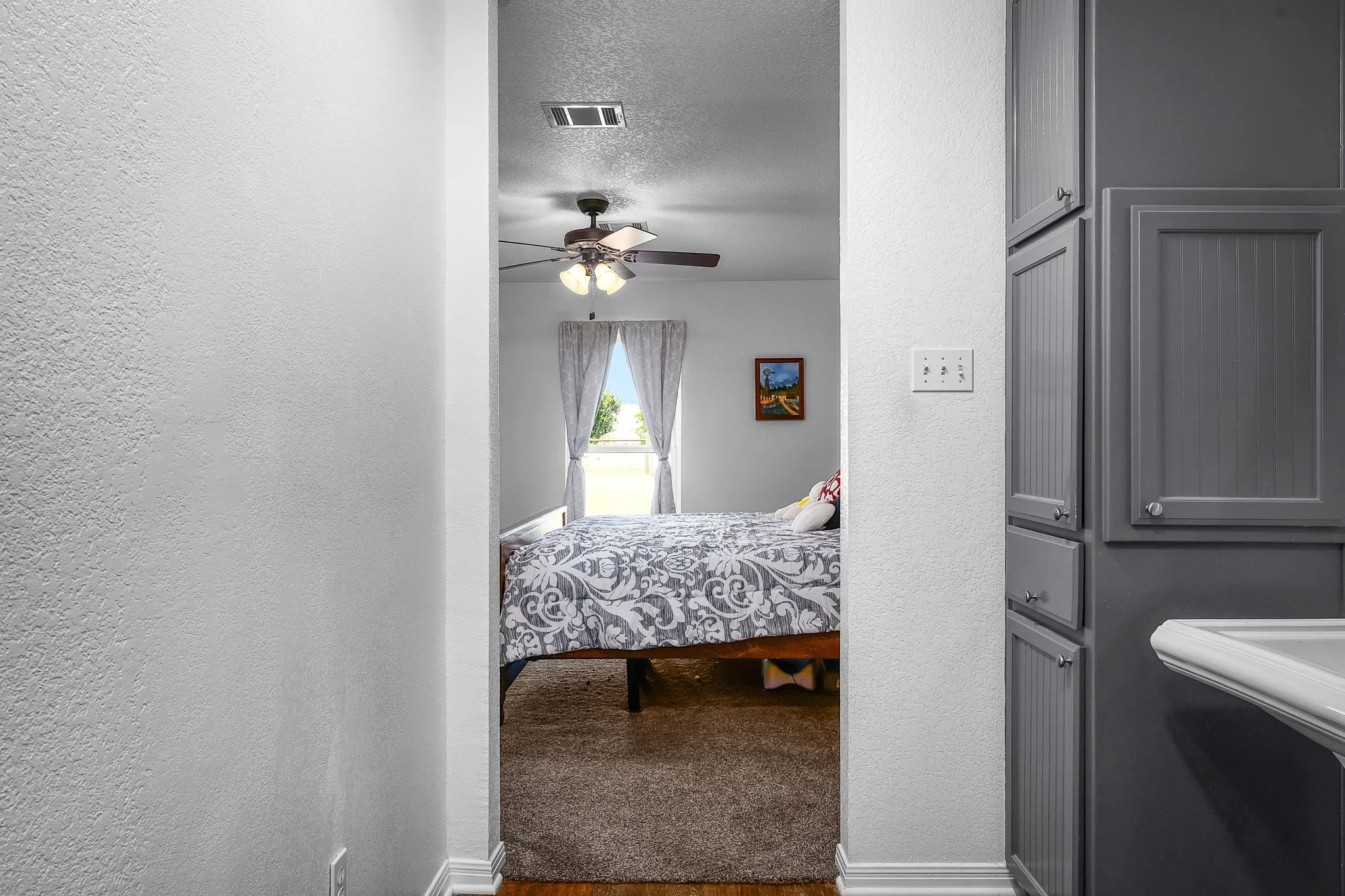Light-filled interior space featuring a ceiling fan, a window, wood-finish flooring, and white baseboards