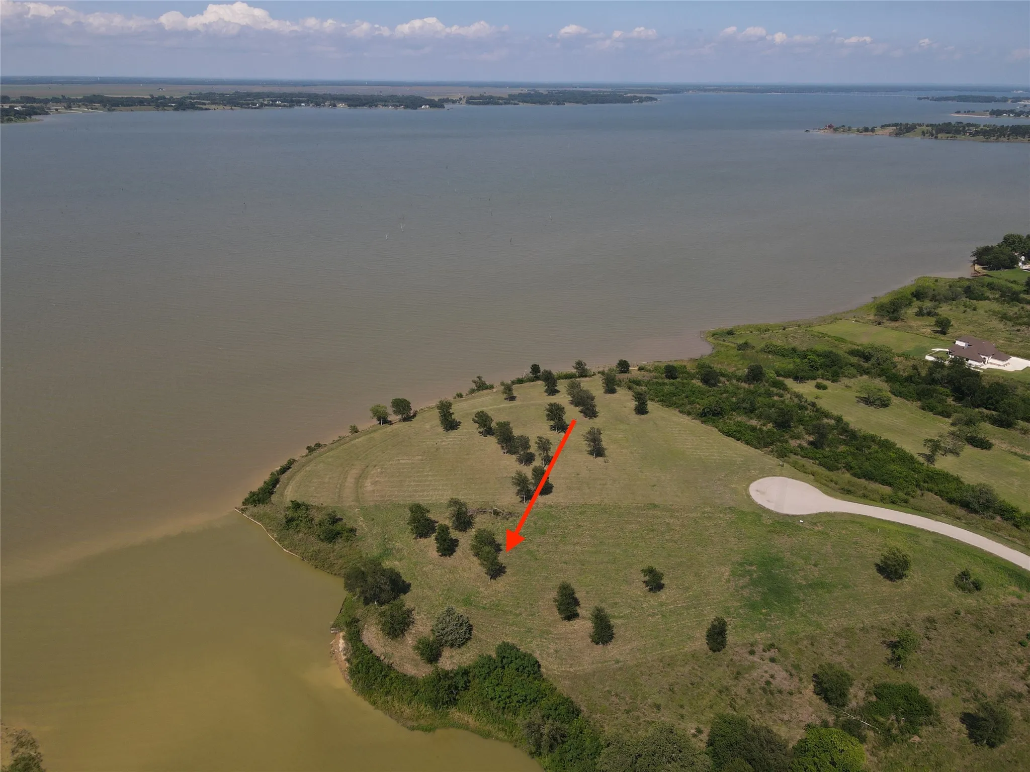 Waterfront acreage featuring a gently sloping topography and mature trees