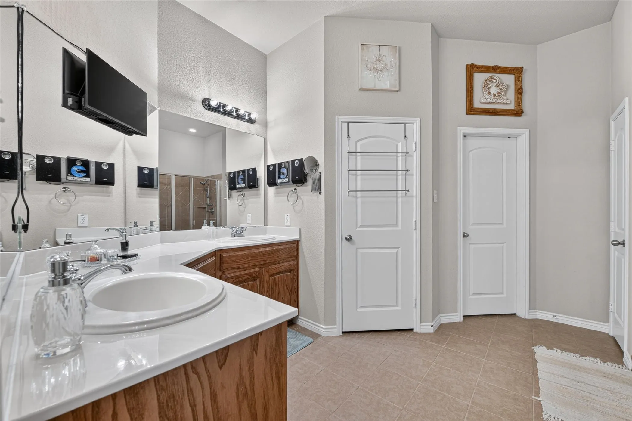Bathroom featuring dual undermount sinks set in a white countertop with wood-finish cabinetry