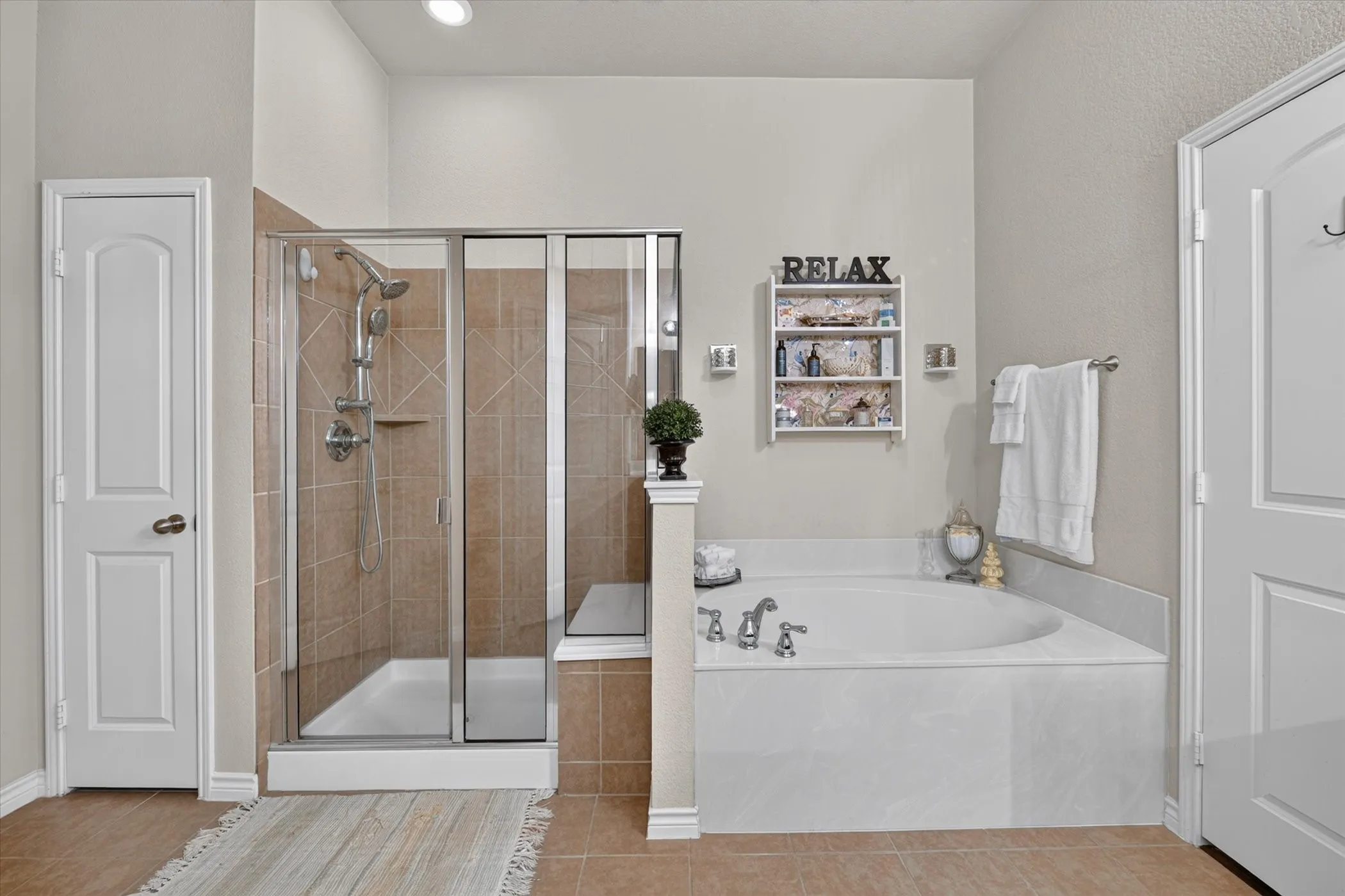 Bathroom featuring a built-in corner soaking tub, a tiled walk-in shower with glass enclosure, recessed lighting, and a neutral color palette