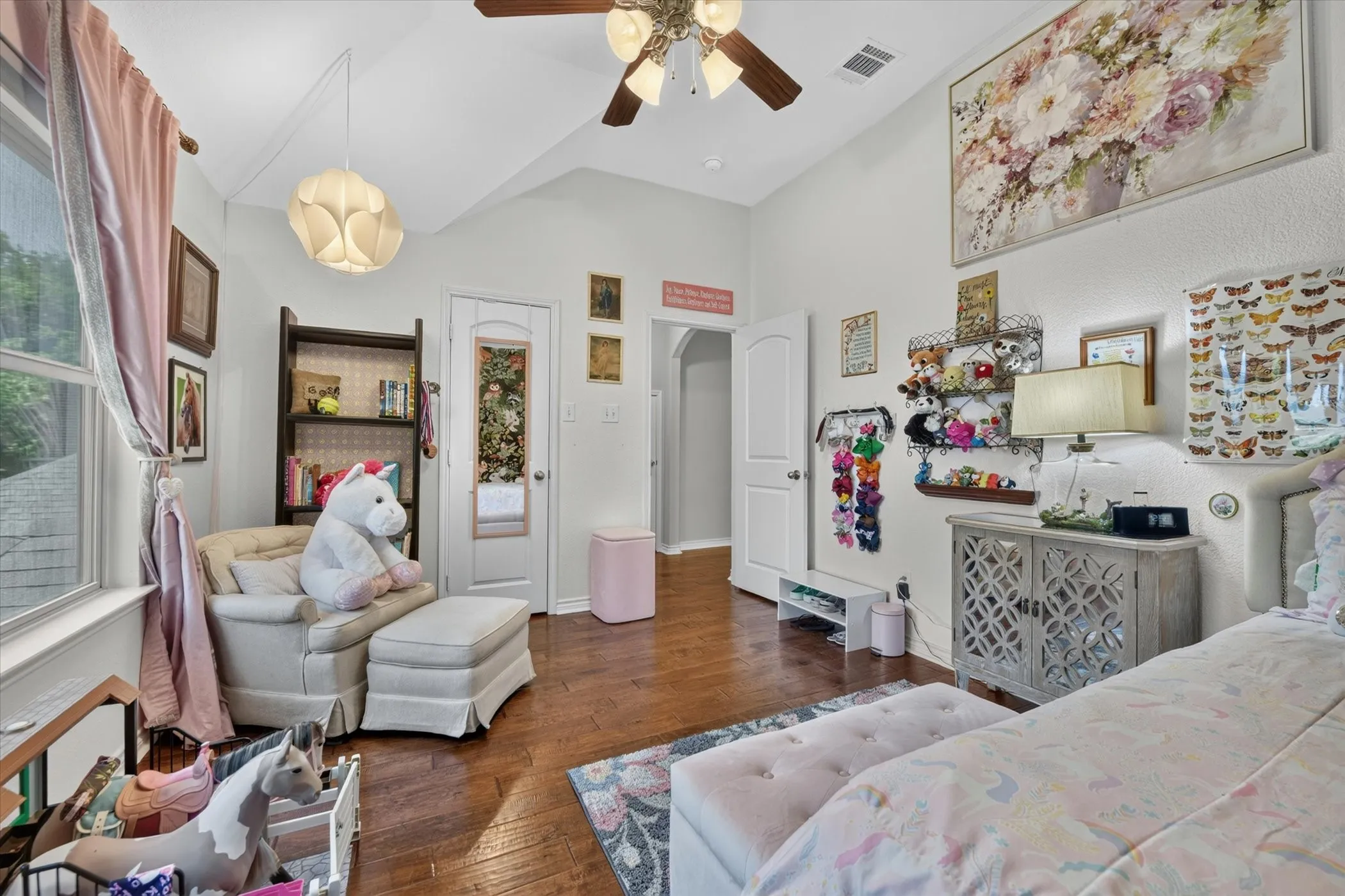 Spacious room featuring vaulted ceilings, wood-finish flooring, a ceiling fan with integrated lighting, and multiple windows