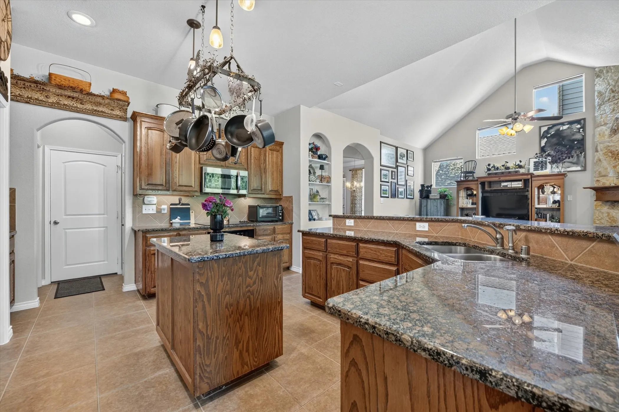 Spacious kitchen featuring an island with stone-finish countertop, wood-finish cabinetry, and tile flooring
