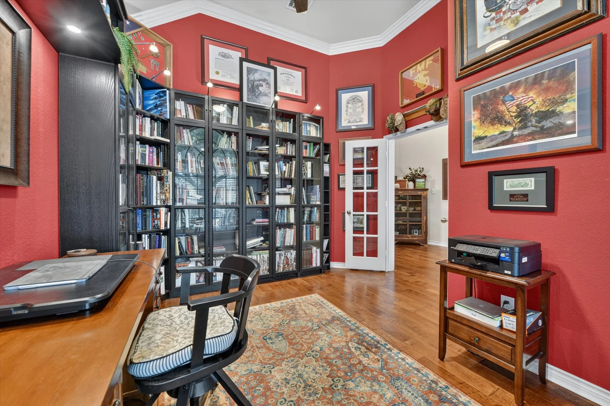 Dedicated study featuring extensive built-in shelving, hardwood flooring, and a French door entry