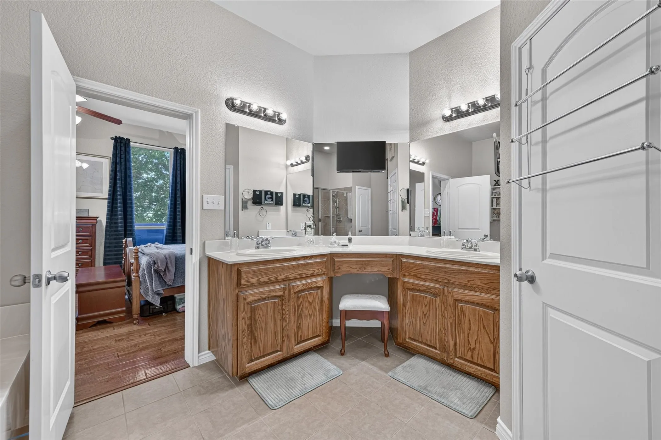 Double vanity with integrated sinks, wood-finish cabinetry, and sconce lighting