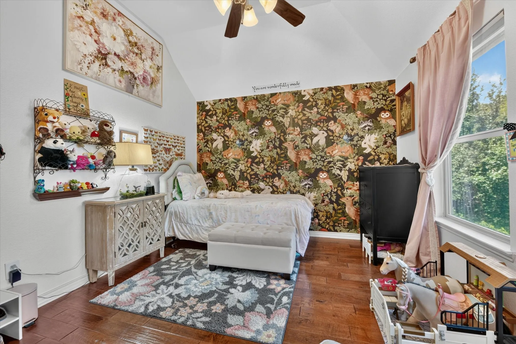 Vaulted ceiling with a ceiling fan, hardwood flooring, and a large window with natural light