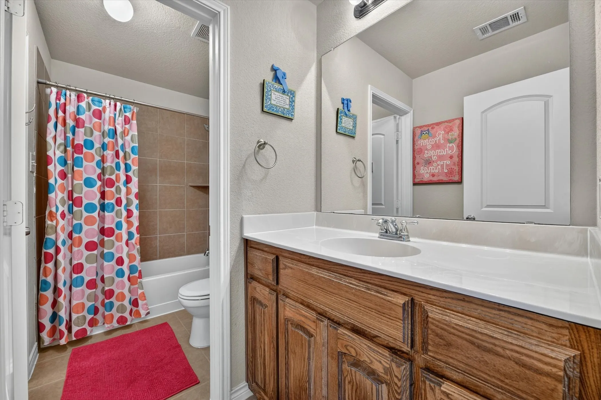 Bathroom featuring a wood-finish vanity with a white countertop and integrated sink