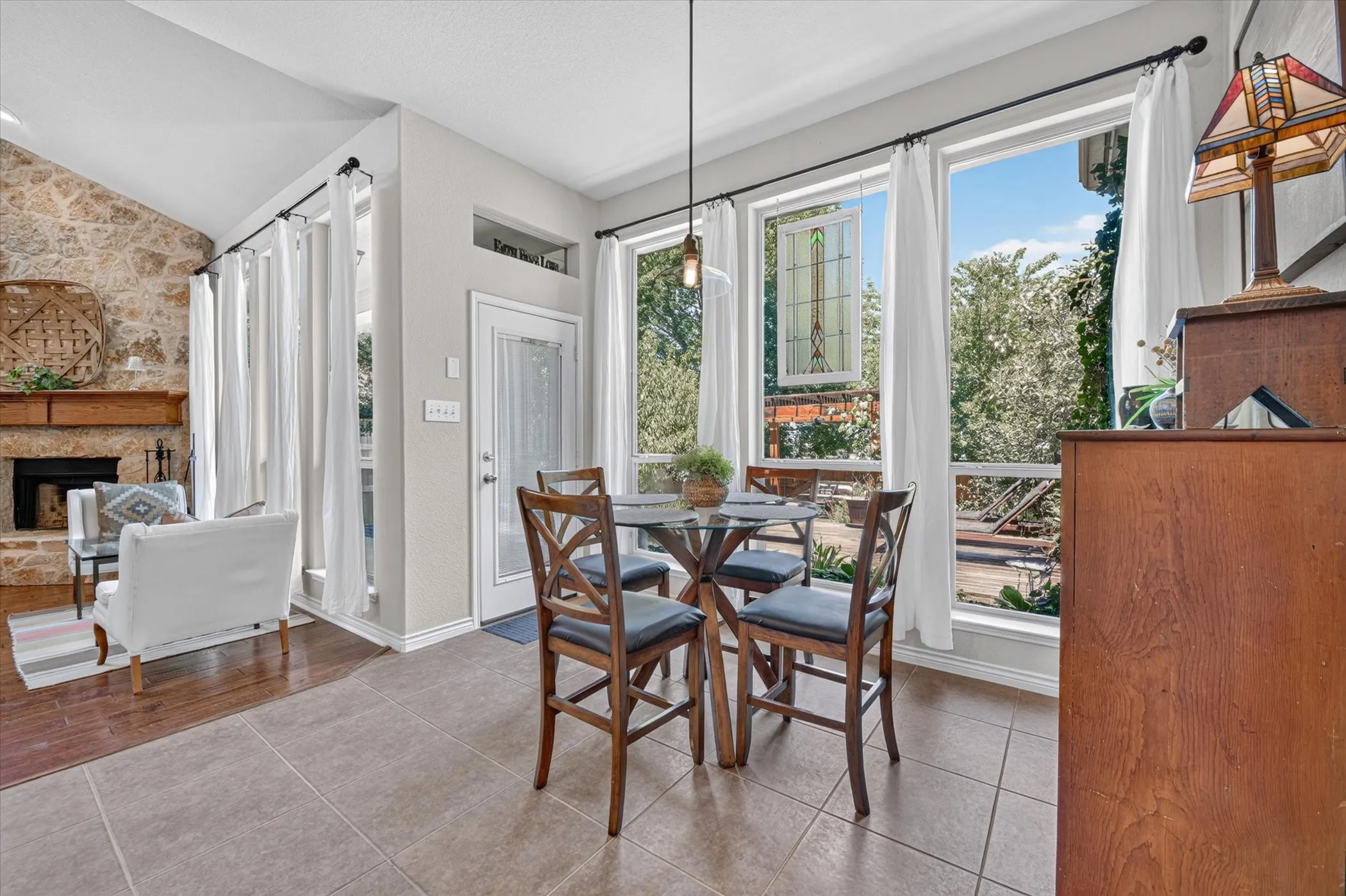 Bright dining area with large windows, tile flooring, and a glass-top table