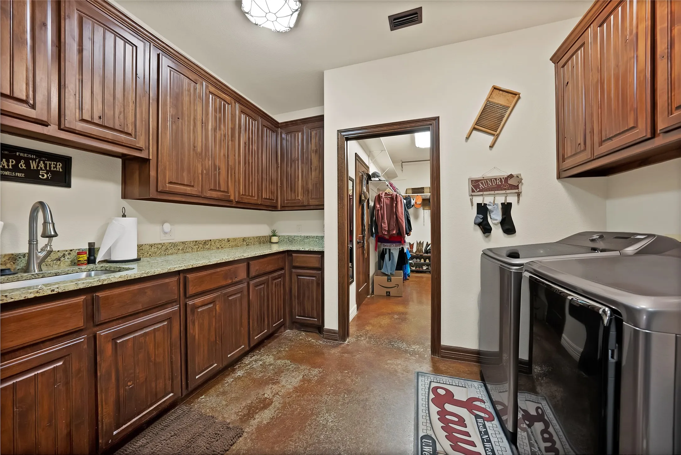 Super sized utility room off garage, leads into primary closet, sink and lots of cabinetry