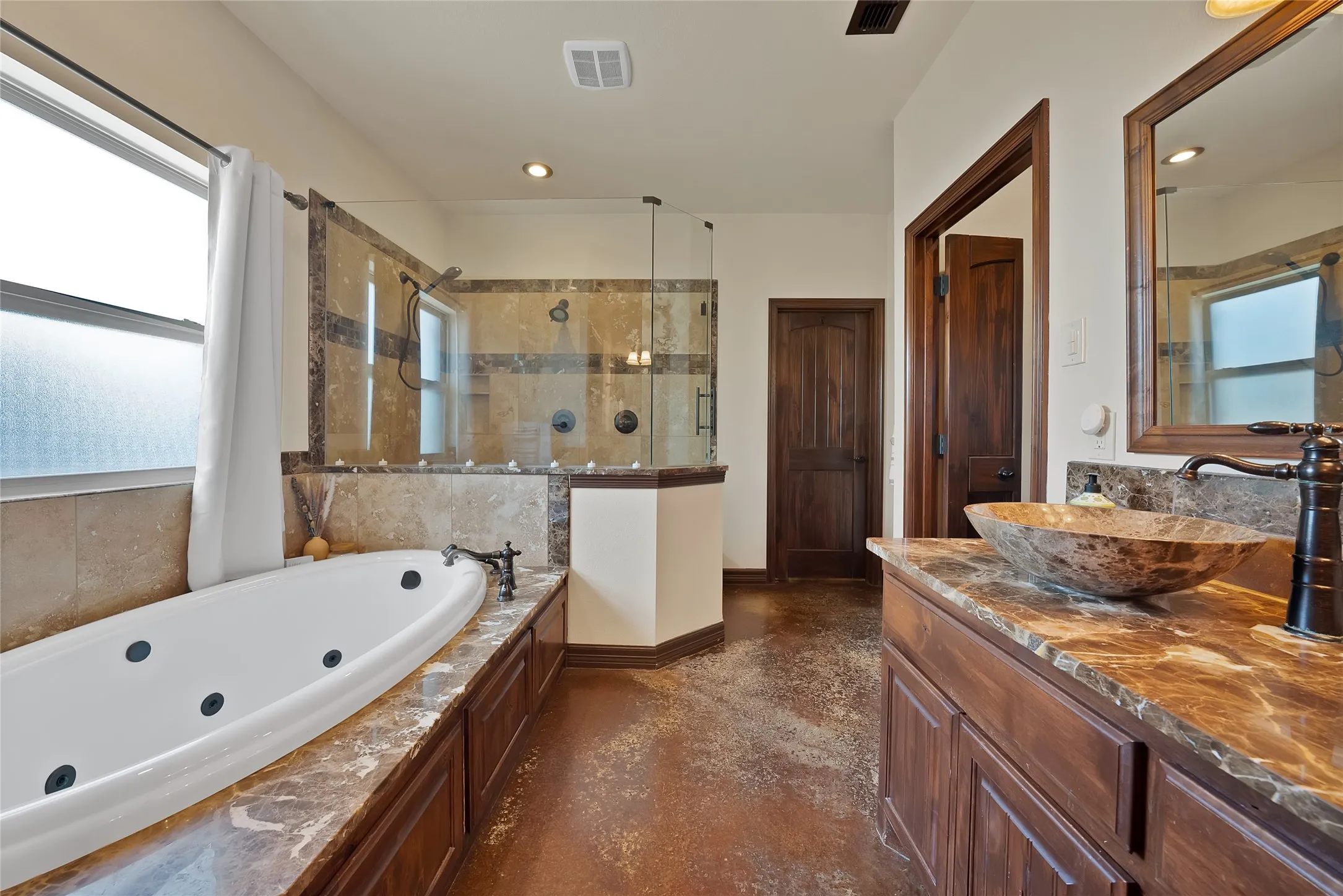 Jetted oversized tub, dual head glass enclosed double size shower with beautiful tile work and nooks