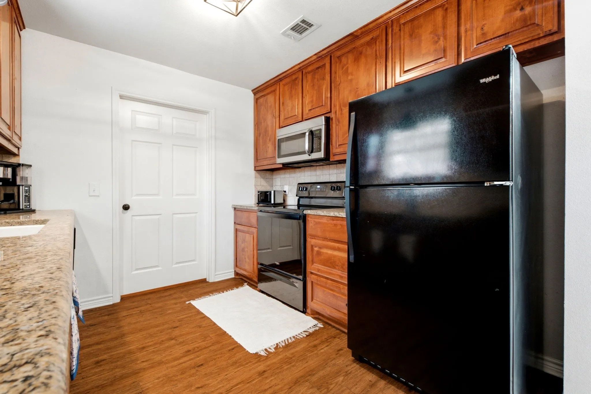 Kitchen includes black and stainless appliances, abundant cabinet space, and easy access to the pantry and laundry area.