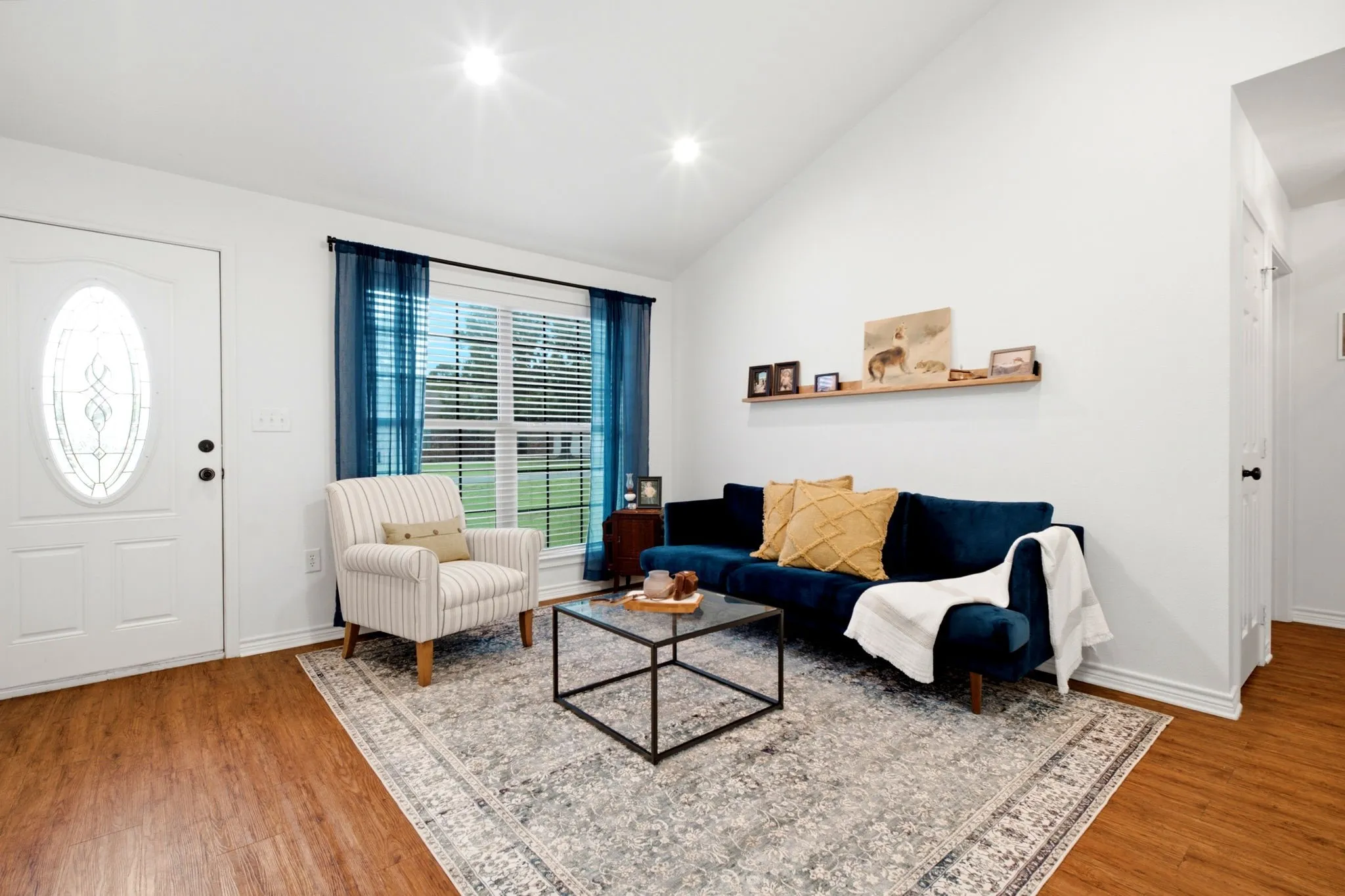 Inviting living room offers a comfortable gathering space with large windows overlooking the front yard.