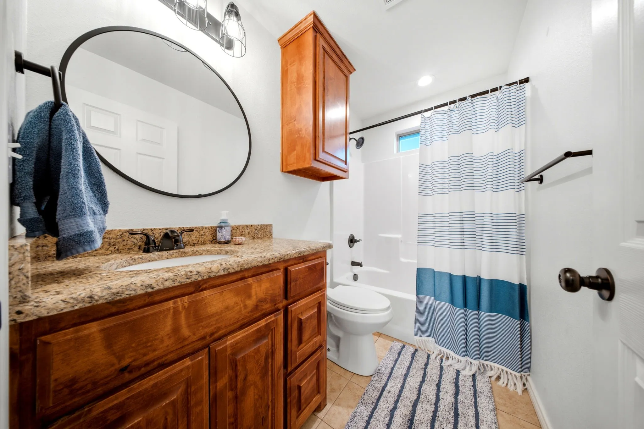 Secondary bathroom features granite countertops, tile flooring, and a tub-shower combination for family and guests.